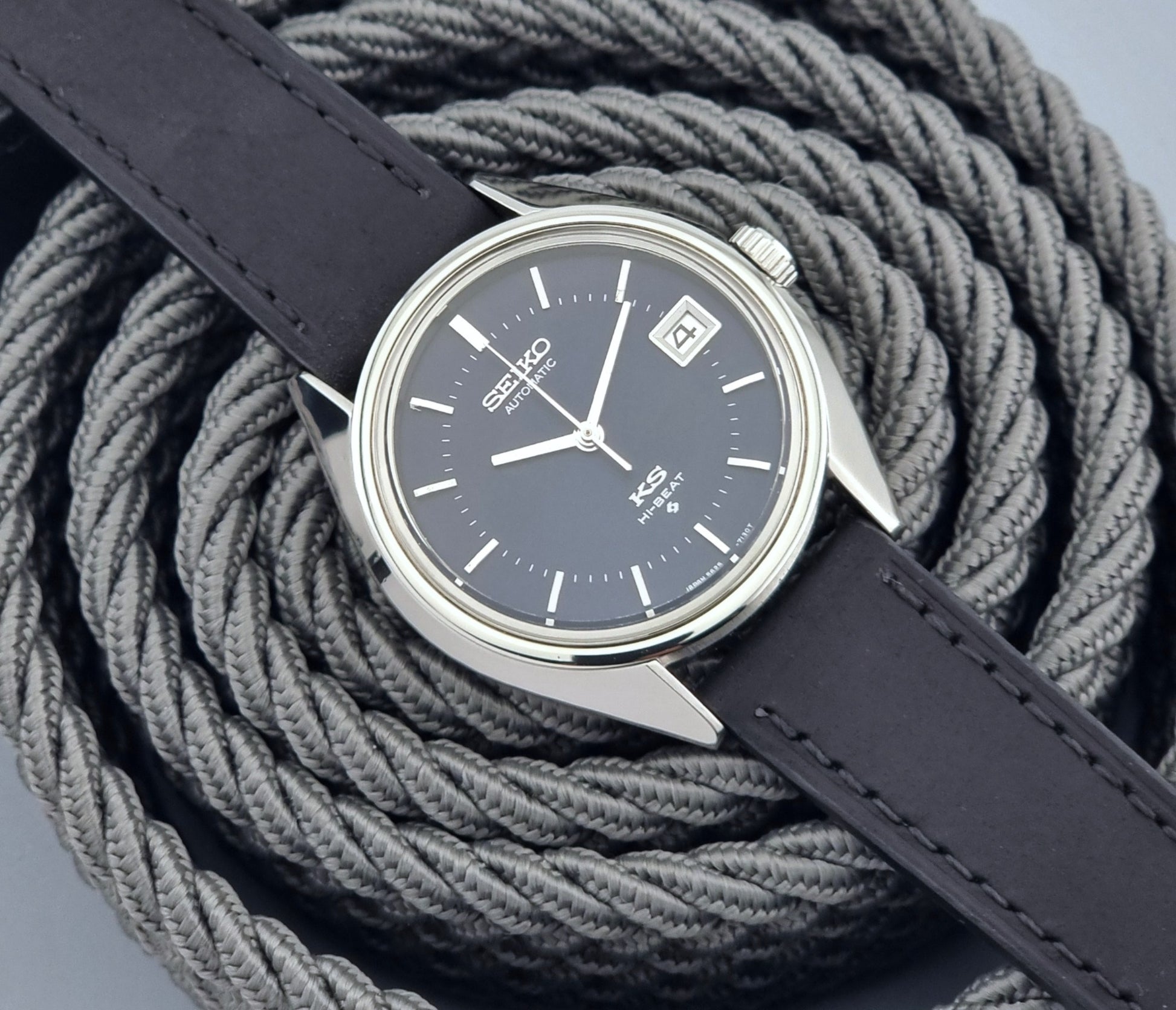 Vintage King Seiko watch with dark blue face and leather strap on a textured gray background