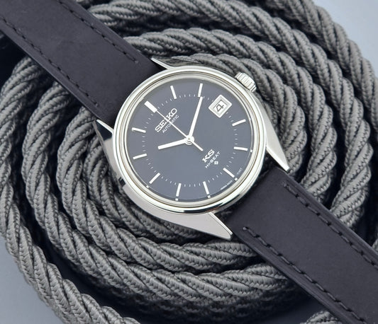 Vintage King Seiko watch with dark blue face and leather strap on a textured gray background