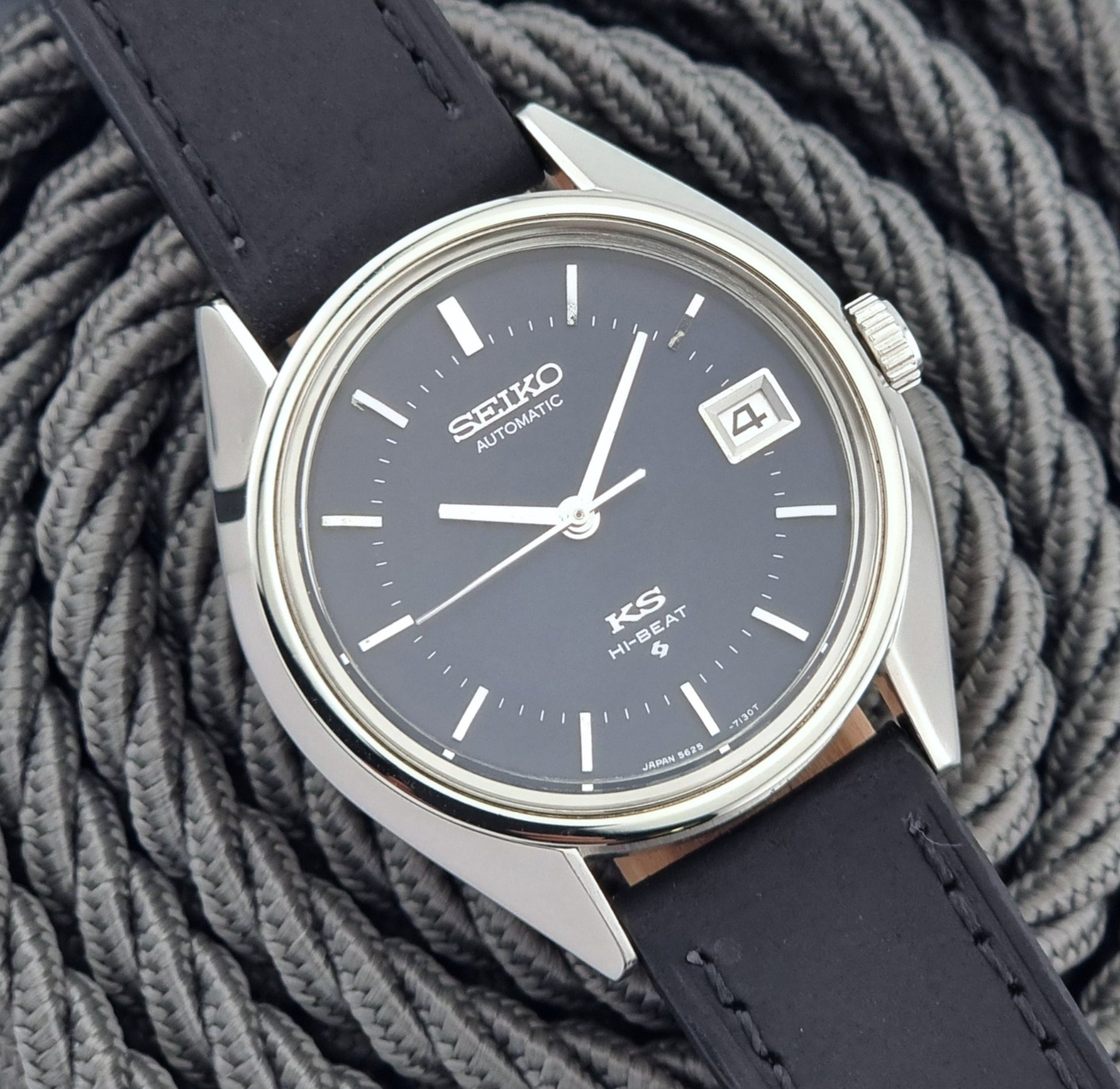 Vintage King Seiko watch with black leather strap on a textured gray background