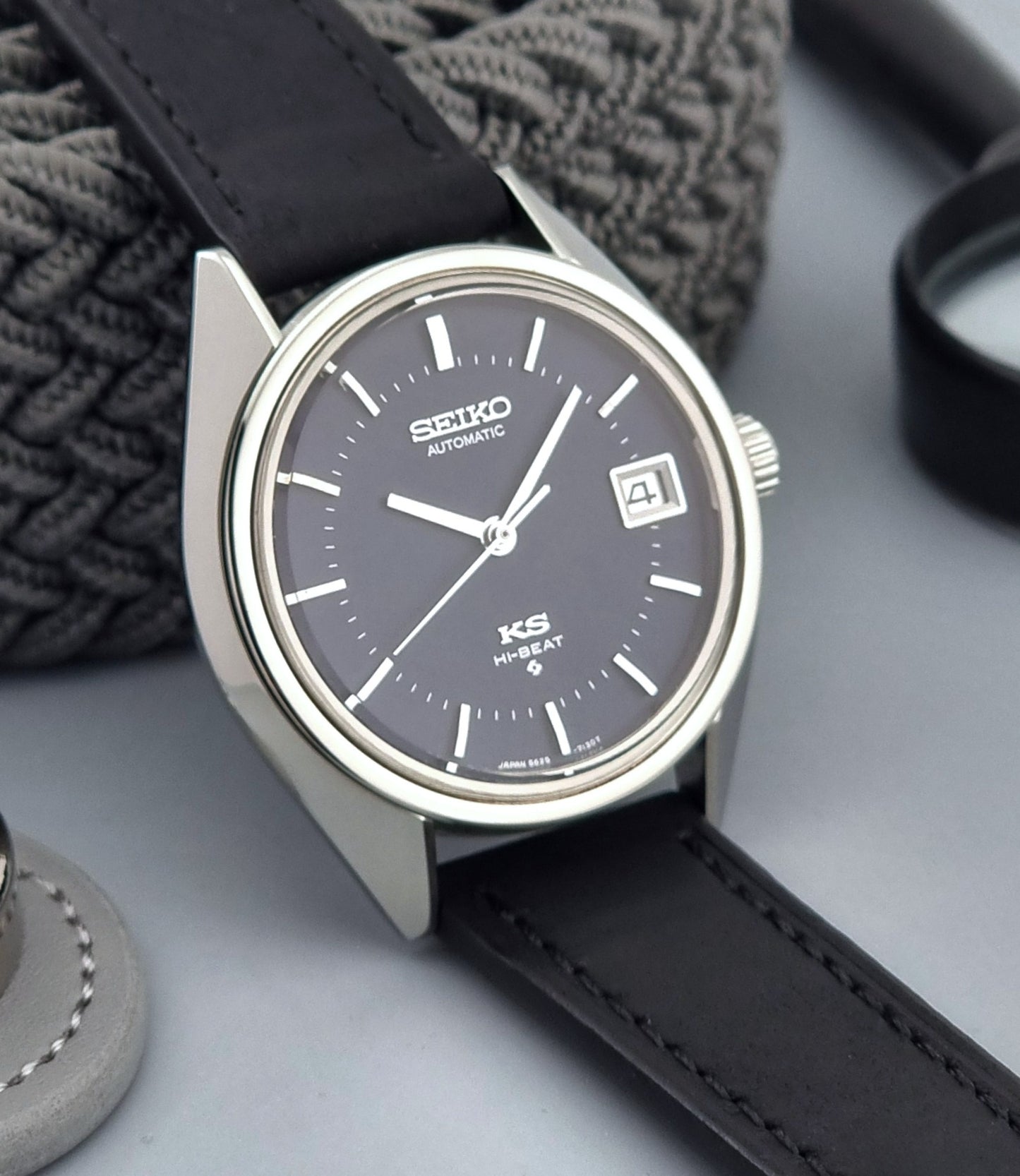 Vintage King Seiko watch with black leather strap on a gray surface