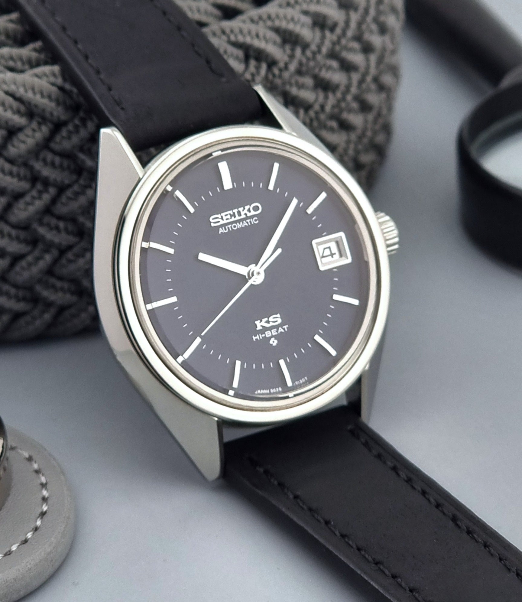 Vintage King Seiko watch with black leather strap on a gray surface