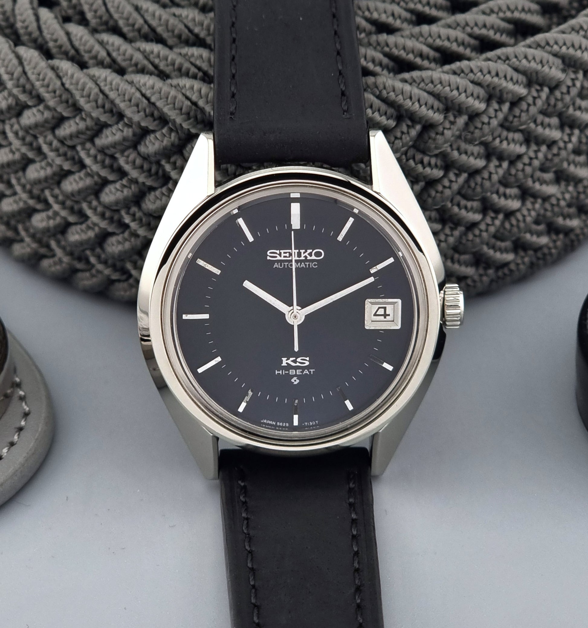 Vintage King Seiko watch with black leather strap on a textured surface