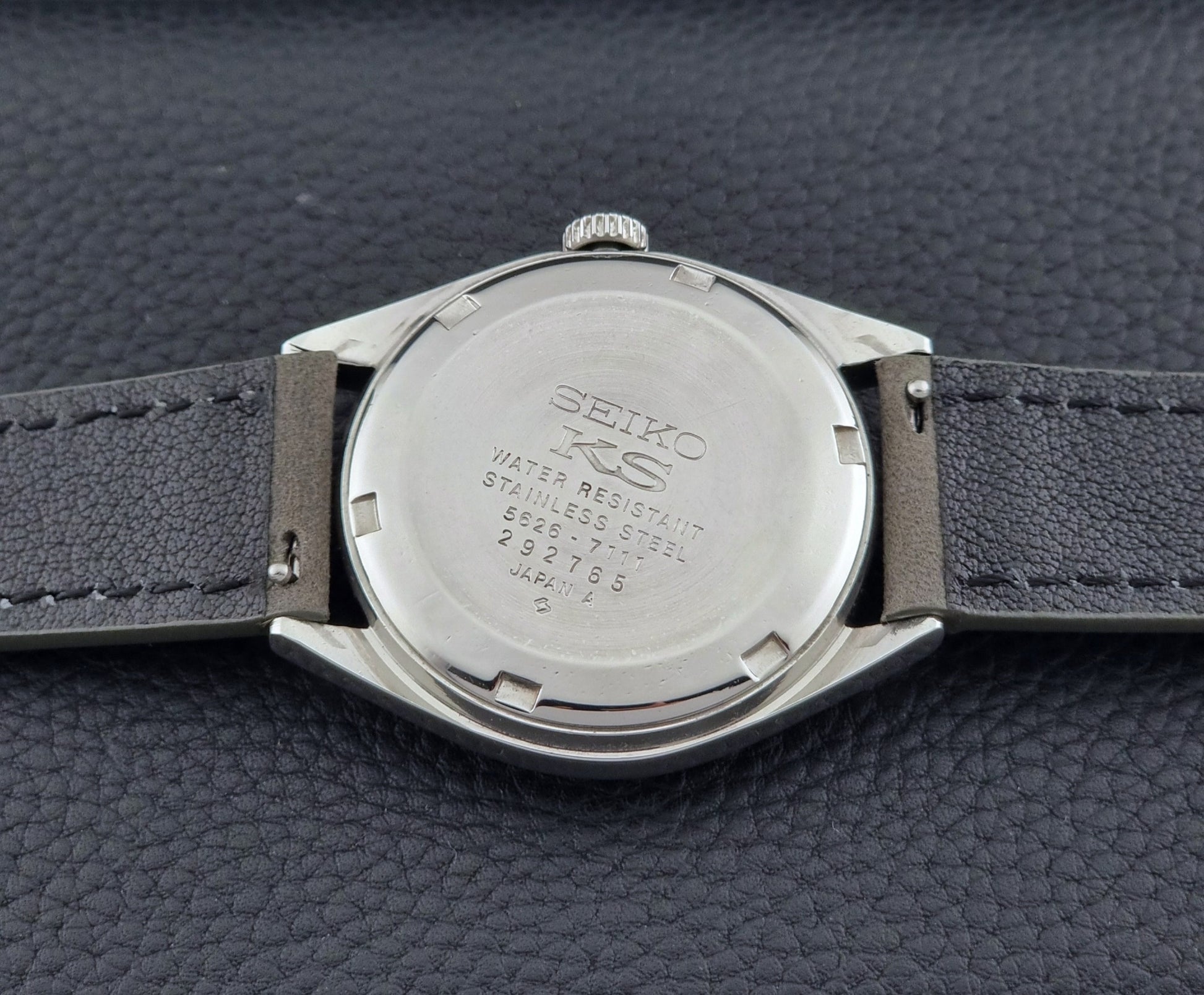 Vintage King Seiko Wristwatch 5626-7111 with a graduated blue dial and gray leather strap on a textured dark background case back