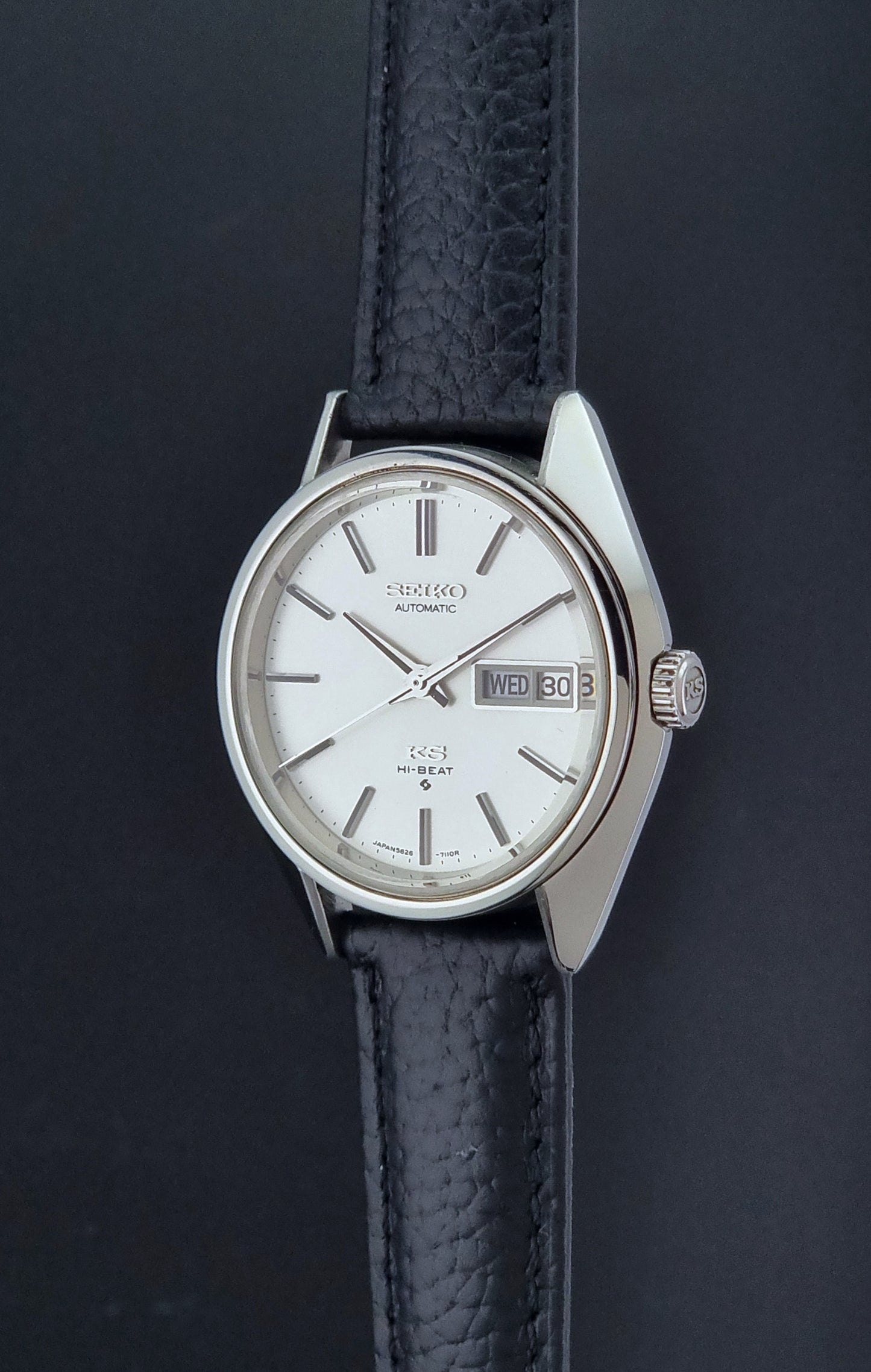 Vintage King Seiko 5626-7111 Wristwatch with a black strap on a dark background crown profile view