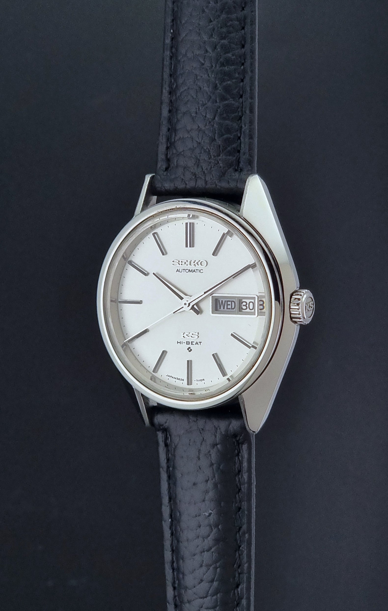 Vintage King Seiko 5626-7111 Wristwatch with a black strap on a dark background crown profile view