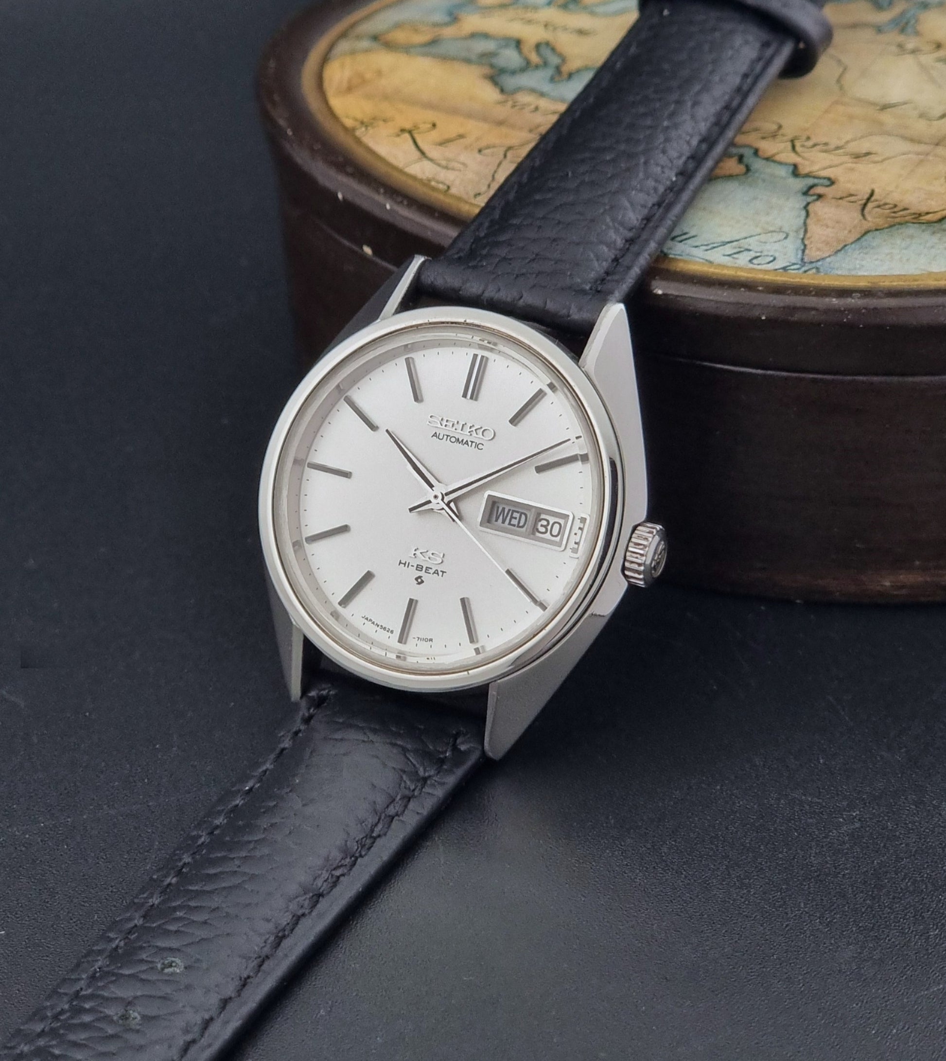 Vintage King Seiko 5626-7111 Wristwatch with a black strap on a dark background crown view