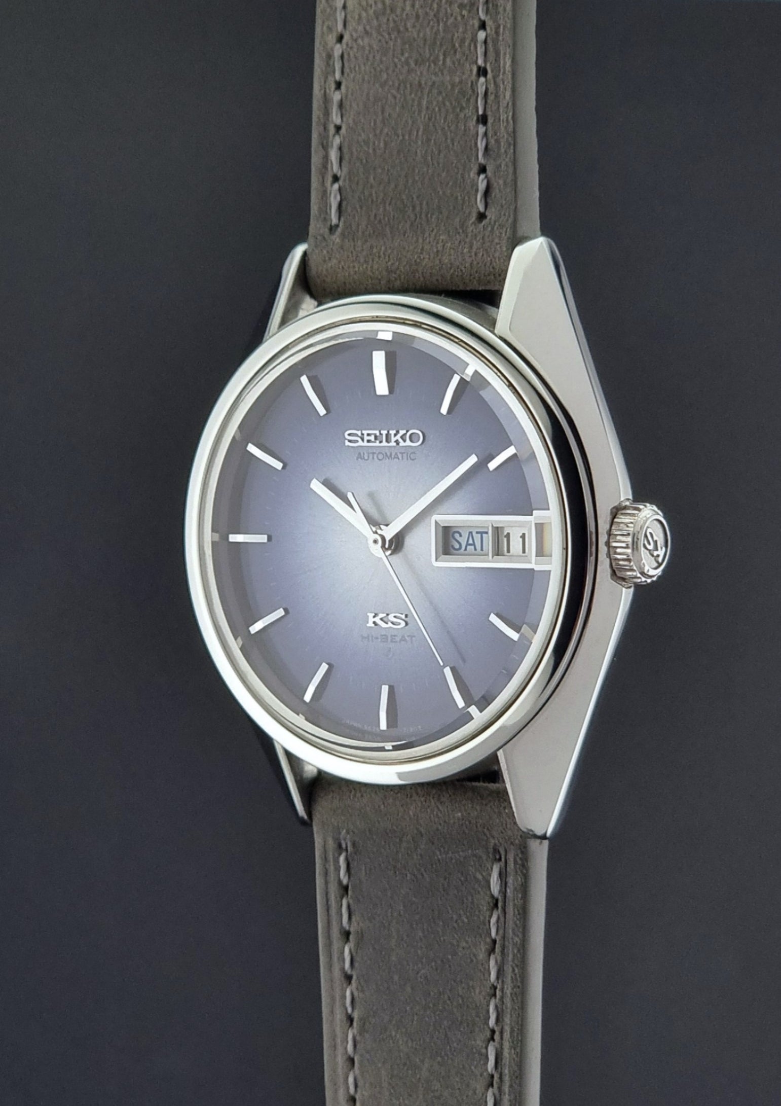 Vintage King Seiko Wristwatch 5626-7111 with a blue dial and gray leather strap on a textured dark background crown side profile