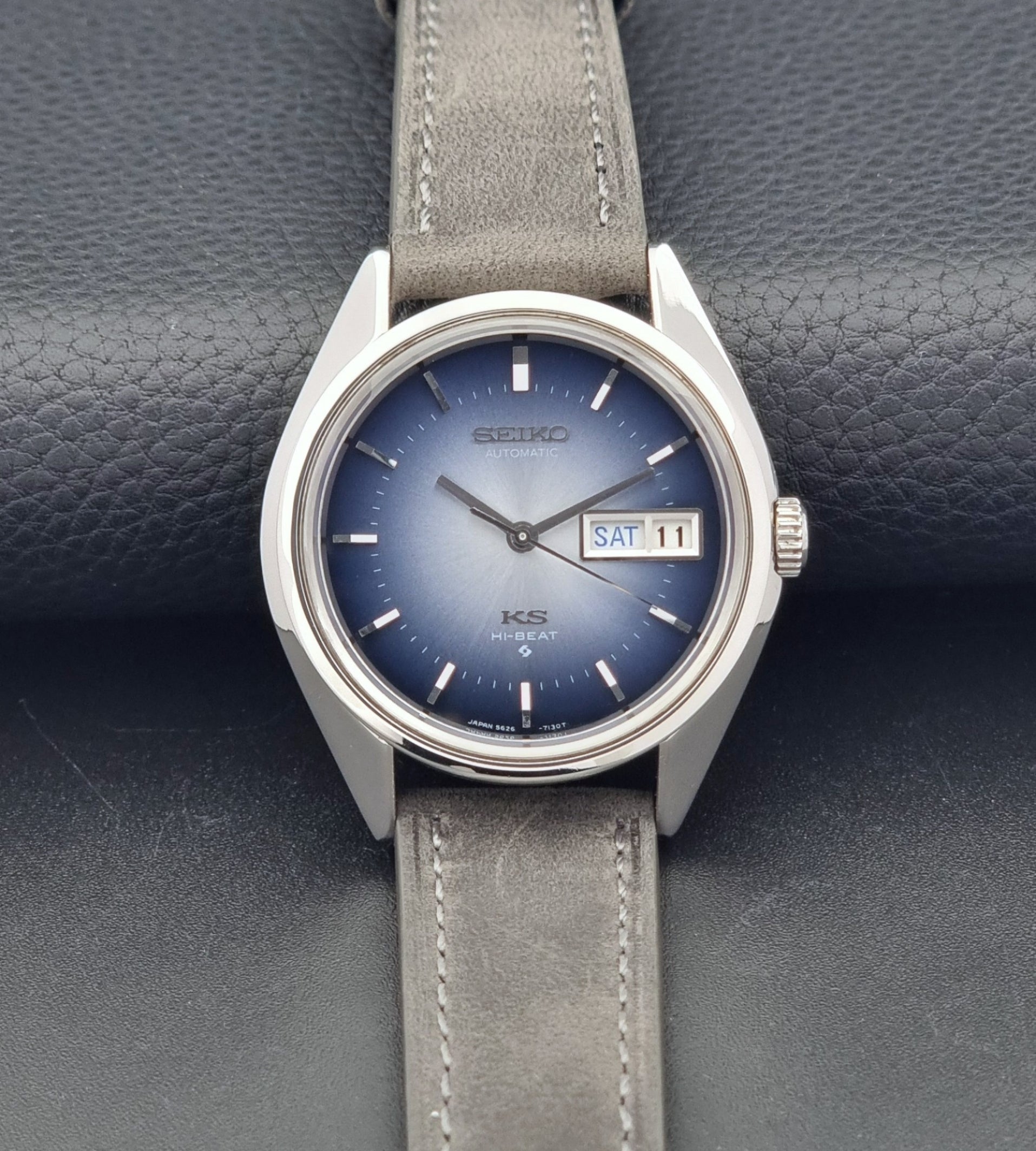 Vintage King Seiko Wristwatch 5626-7111 with a blue dial and gray leather strap on a textured dark background front