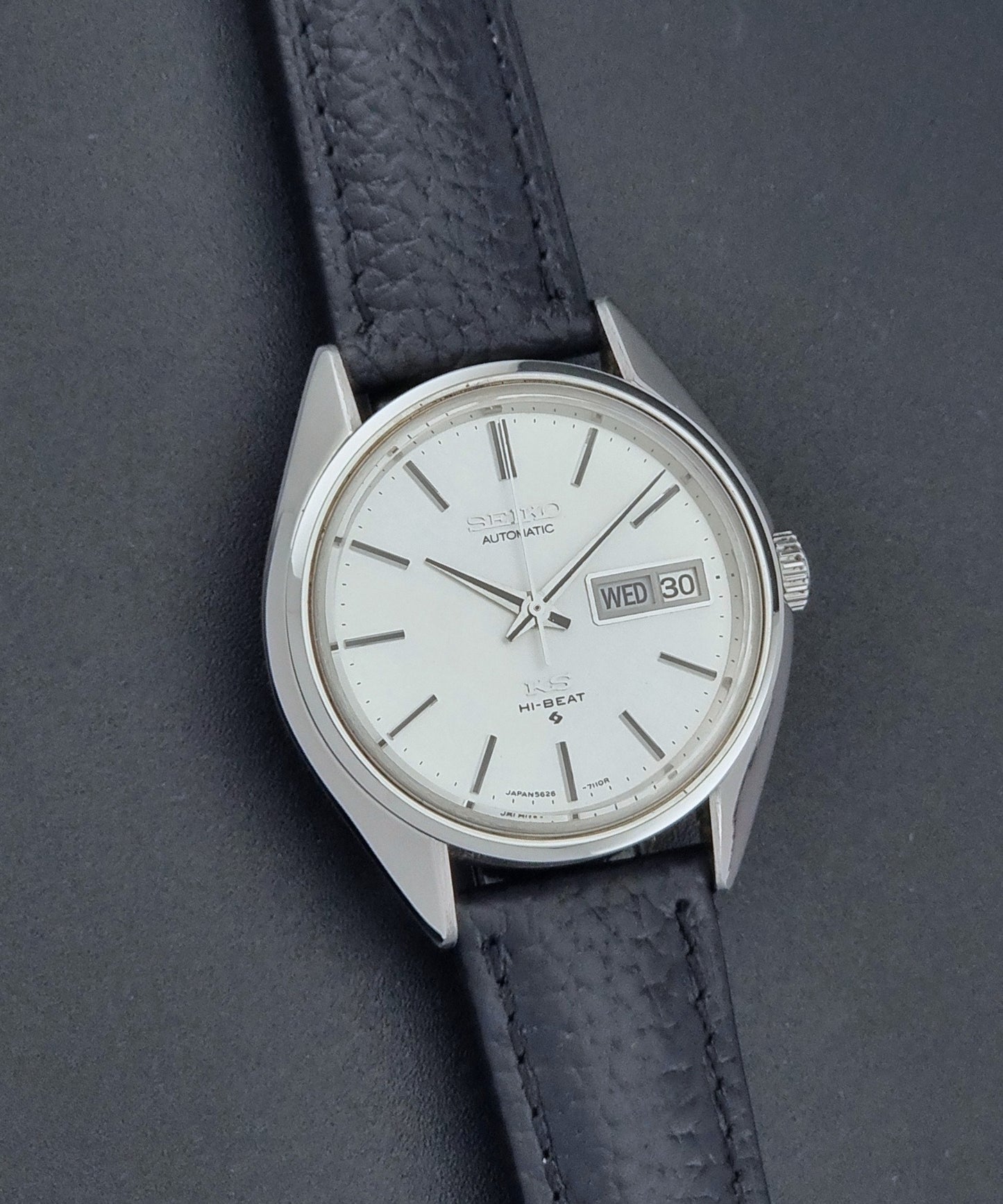 Vintage King Seiko 5626-7111 Wristwatch with a black strap on a dark background front view