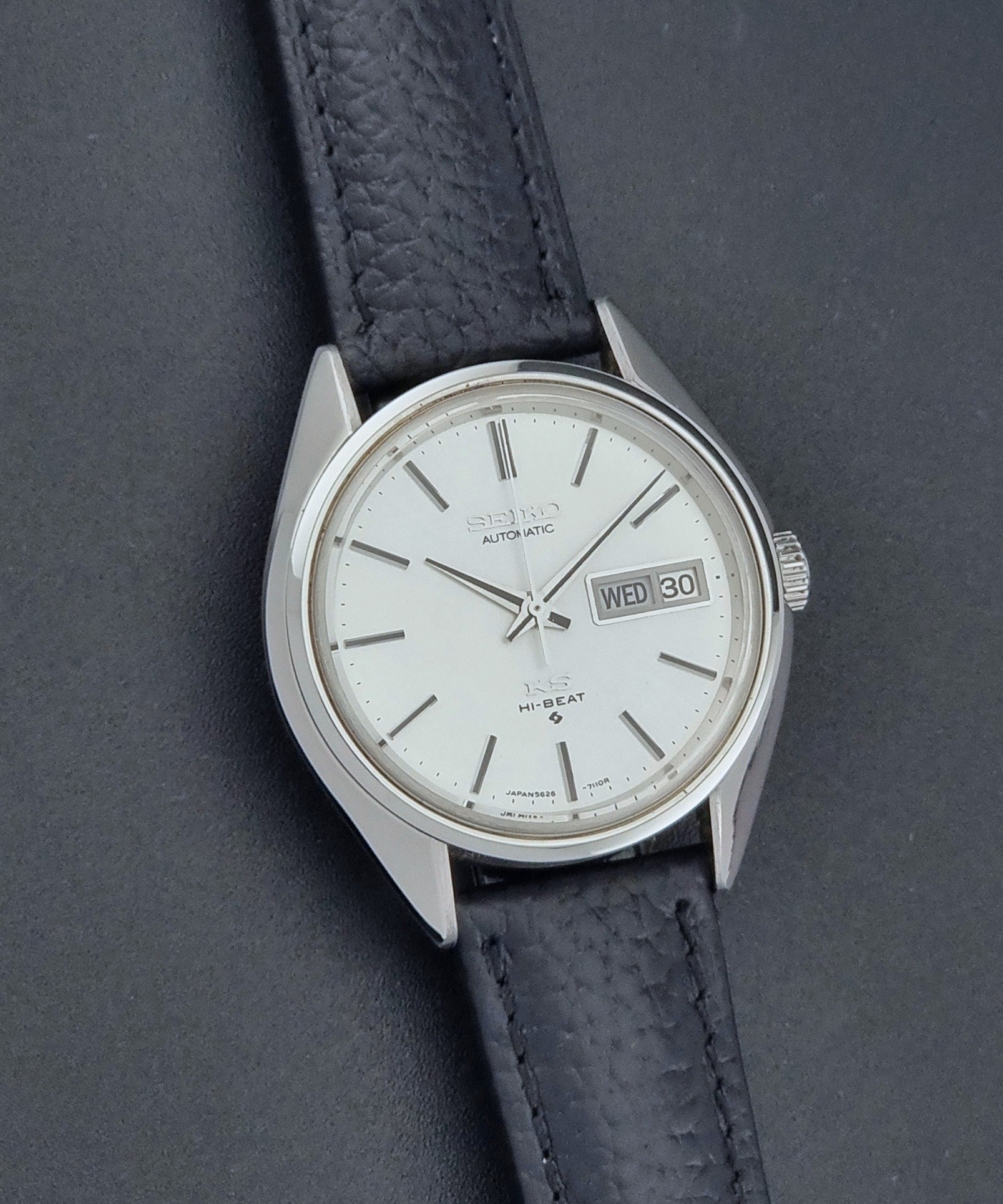 Vintage King Seiko 5626-7111 Wristwatch with a black strap on a dark background front view