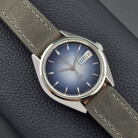 Vintage King Seiko Wristwatch 5626-7111 with a blue dial and gray leather strap on a textured dark background