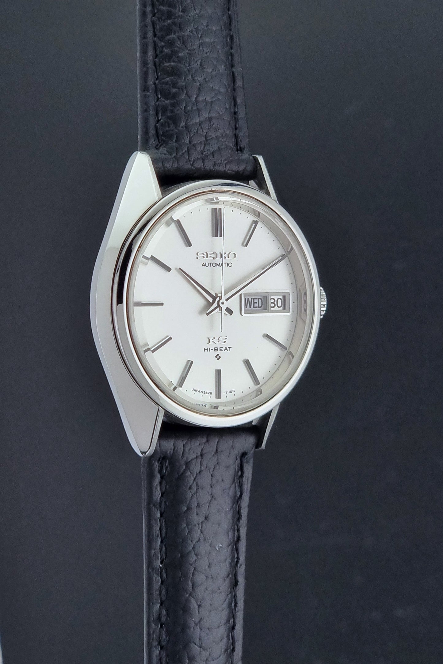 Vintage King Seiko 5626-7111 Wristwatch with a black strap on a dark background side profile view