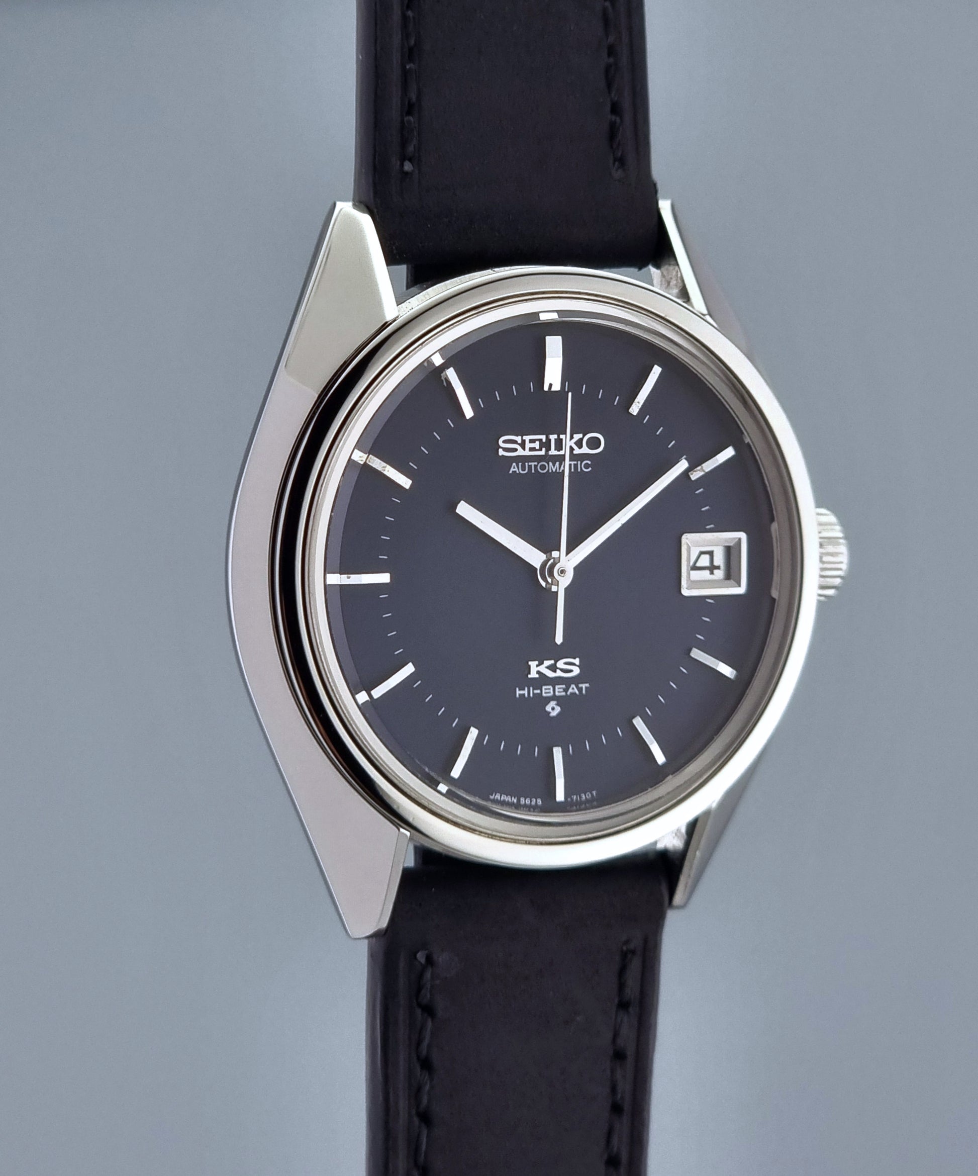 Vintage King Seiko watch with black leather strap and dark blue dial on a gray background