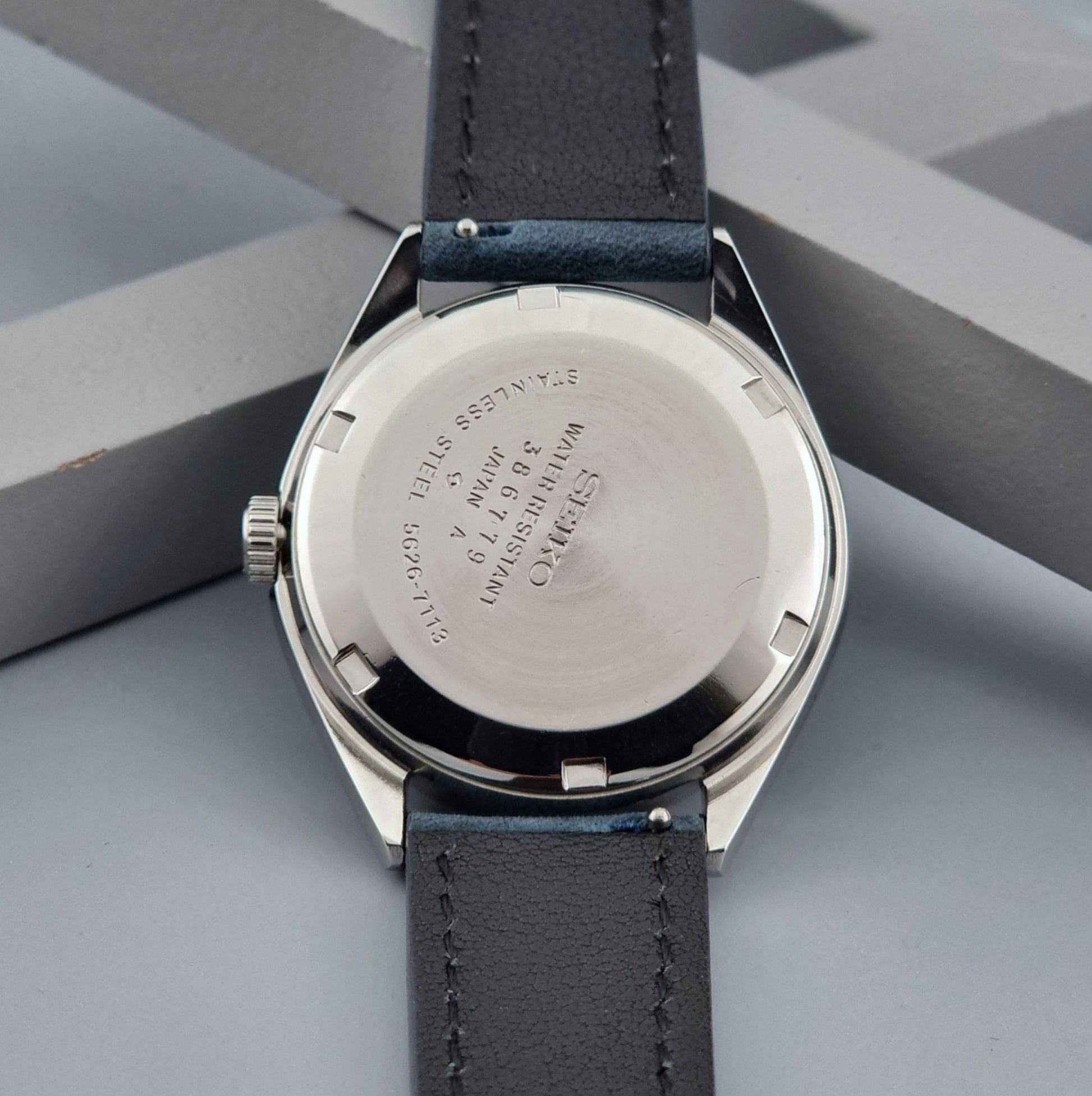 Vintage King Seiko wristwatch with a blue strap on a gray background case back view