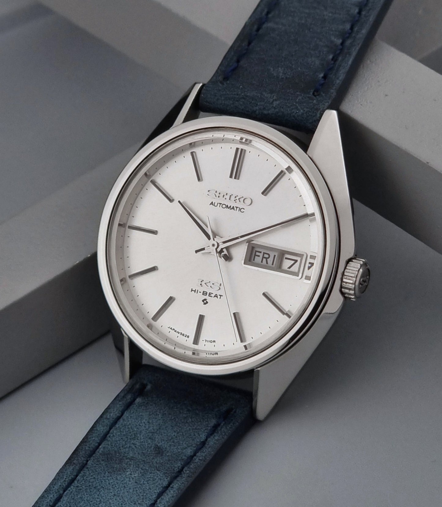 Vintage King Seiko wristwatch with a blue strap on a gray background crown view