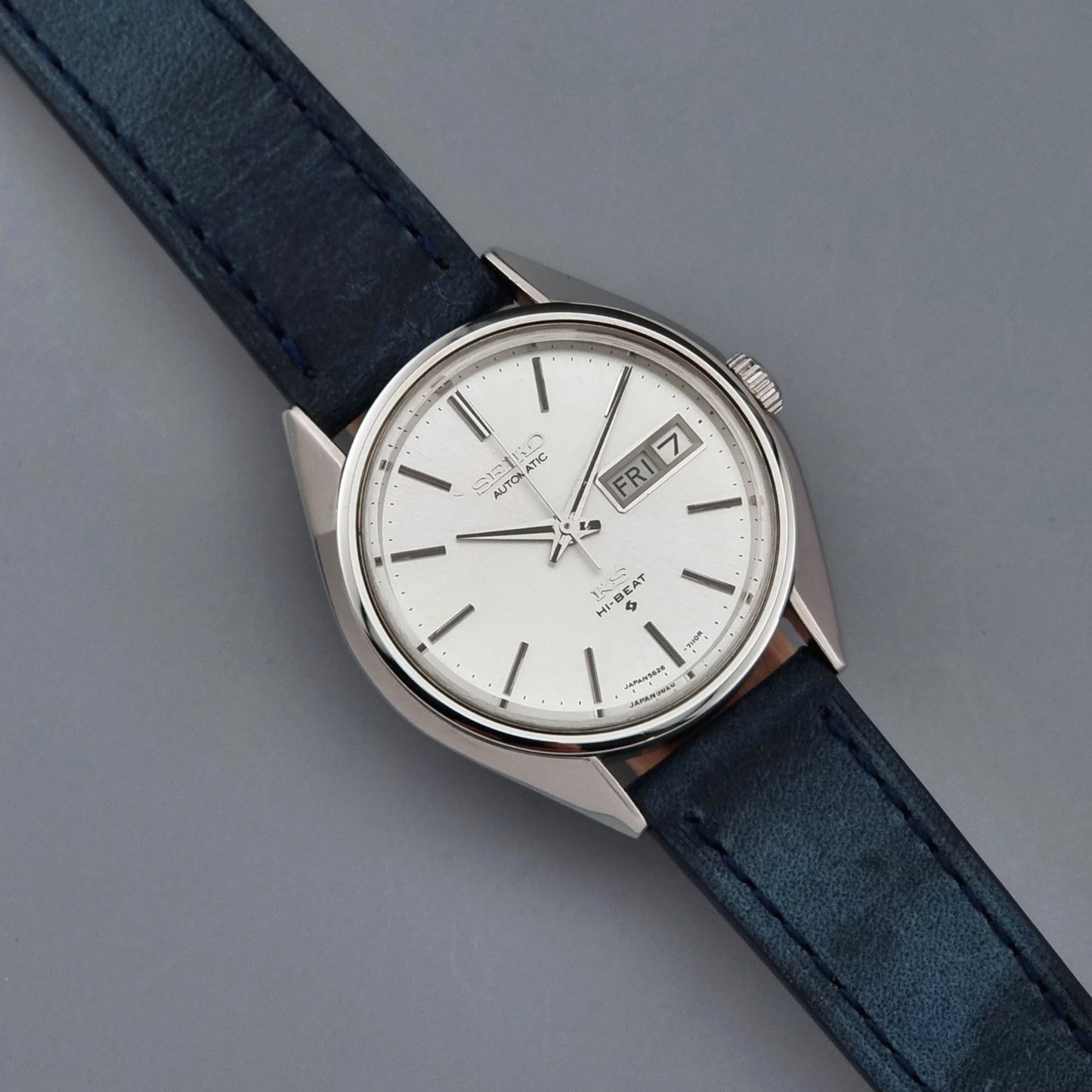 Vintage King Seiko wristwatch with a blue strap on a gray background dial view