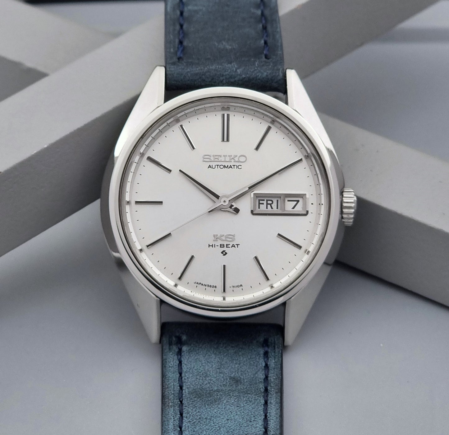 Vintage King Seiko wristwatch with a blue strap on a gray background dial