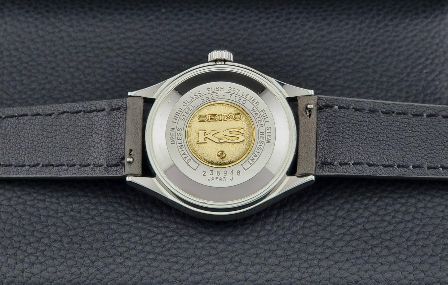 Close-up of a Seiko watch back with a gold emblem on a dark background