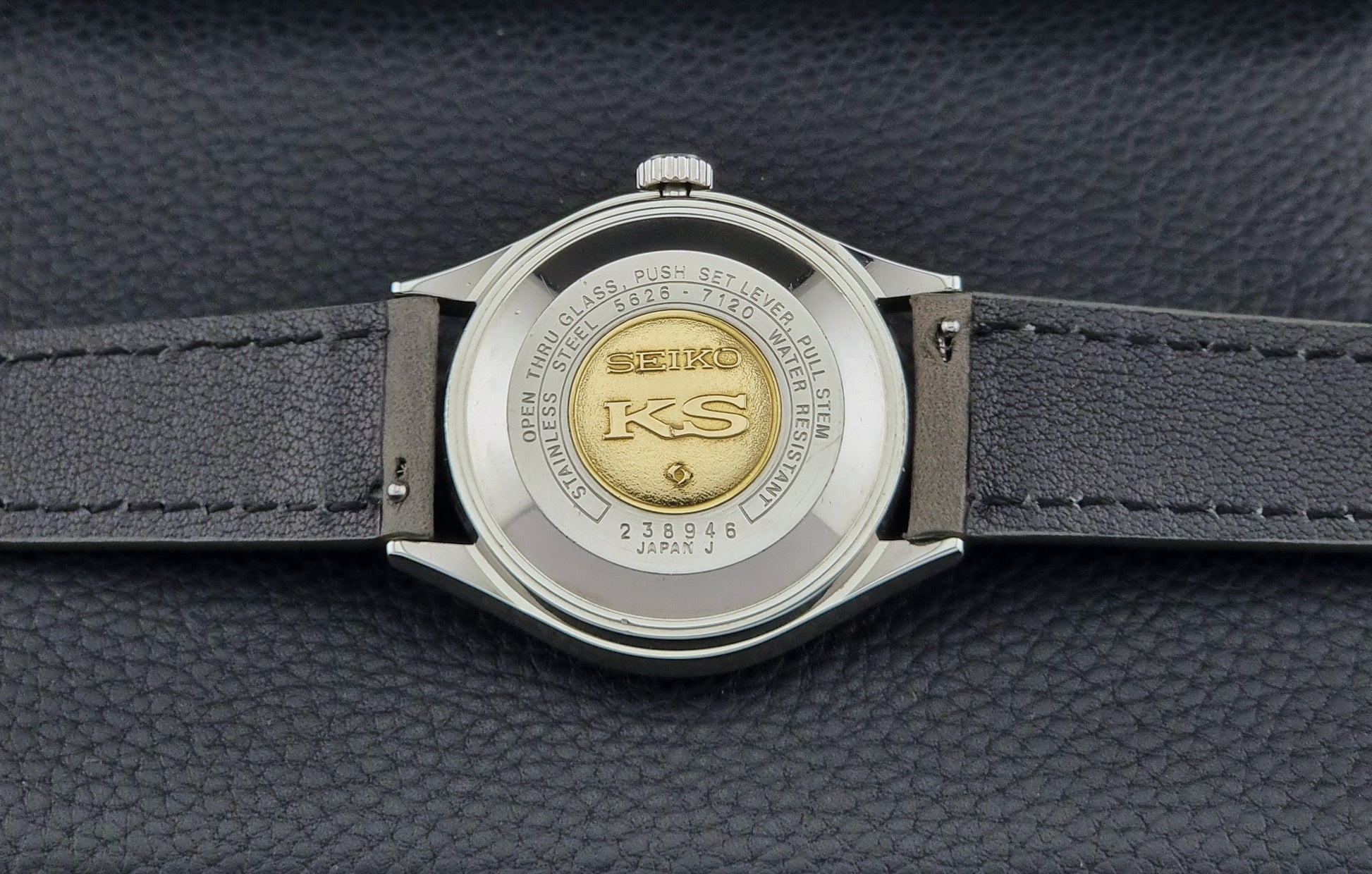 Close-up of a Seiko watch back with a gold emblem on a dark background
