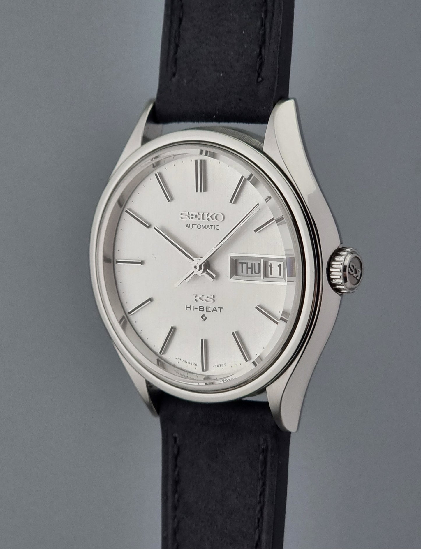 Vintage King Seiko Wristwatch Hi-beat 5626-7120 with a black strap on a grey background crown side profile