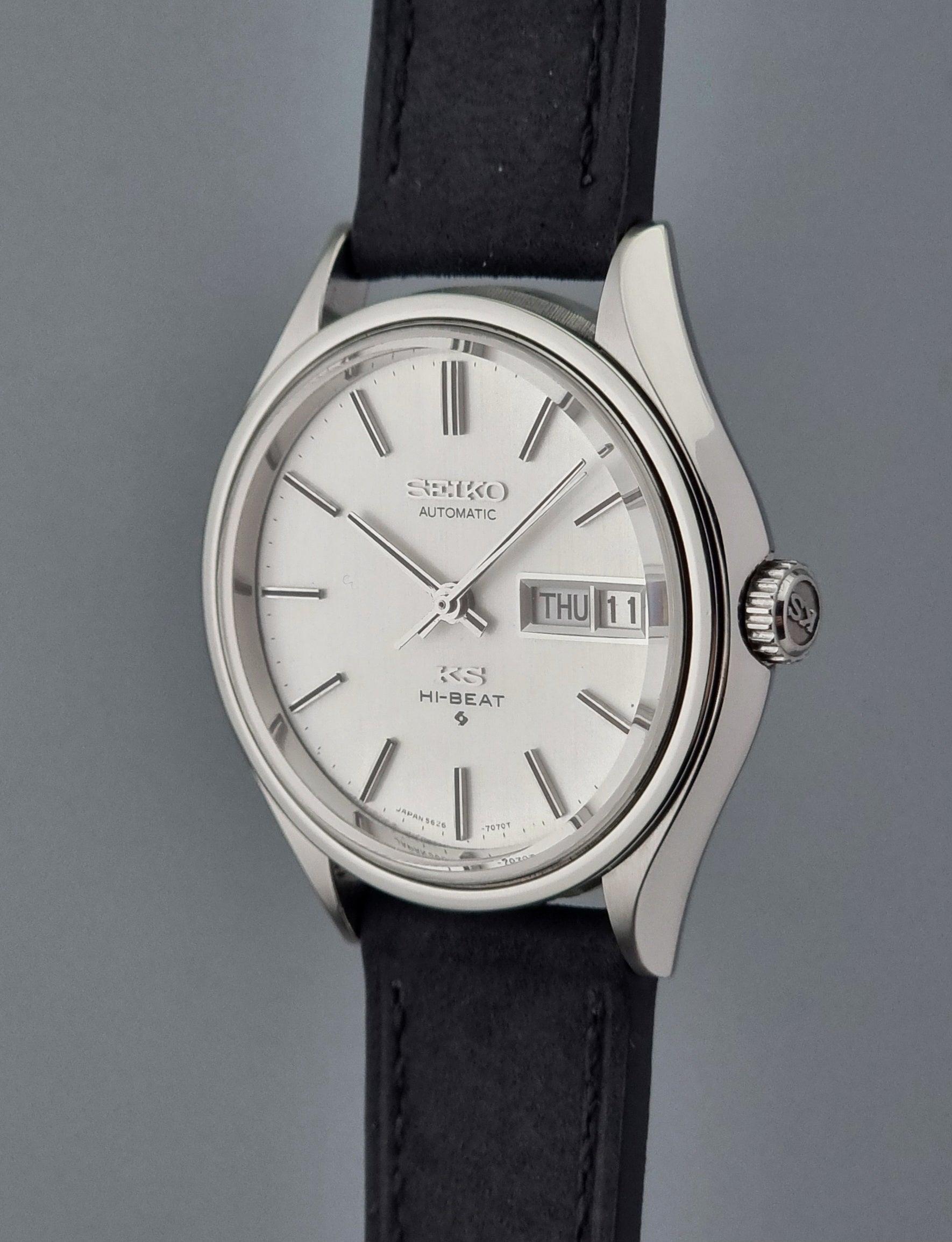 Vintage King Seiko Wristwatch Hi-beat 5626-7120 with a black strap on a grey background crown side profile