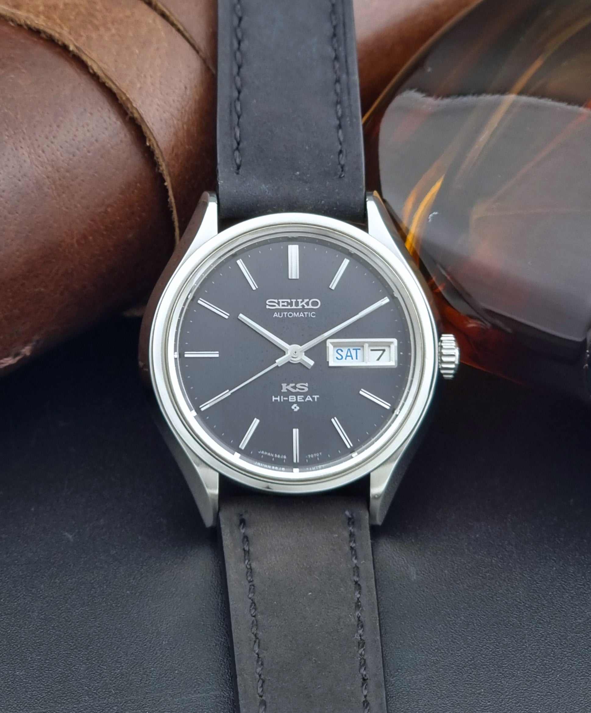 Vintage King Seiko Wristwatch 5626-7120 with black leather strap on a dark surface front view