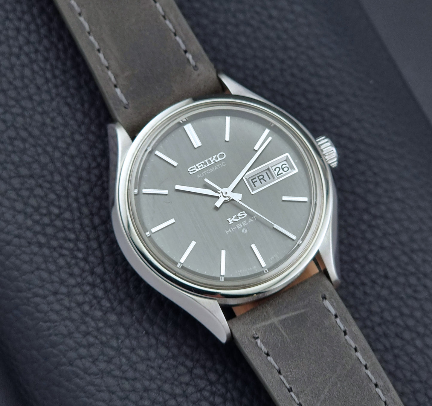 Vintage King Seiko watch with gray strap and gray dial on a dark textured background