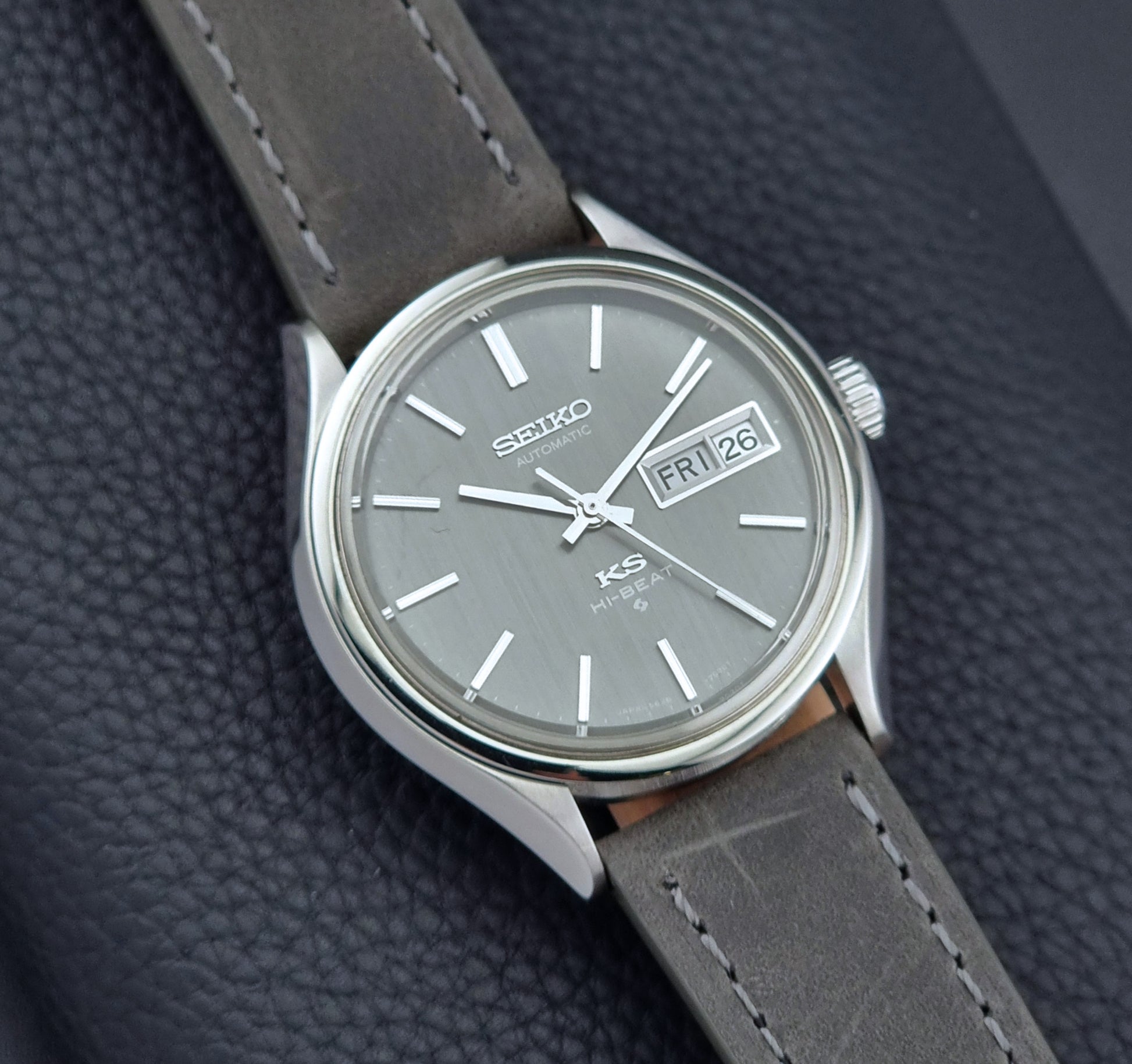 Vintage King Seiko watch with gray strap and gray dial on a dark textured background