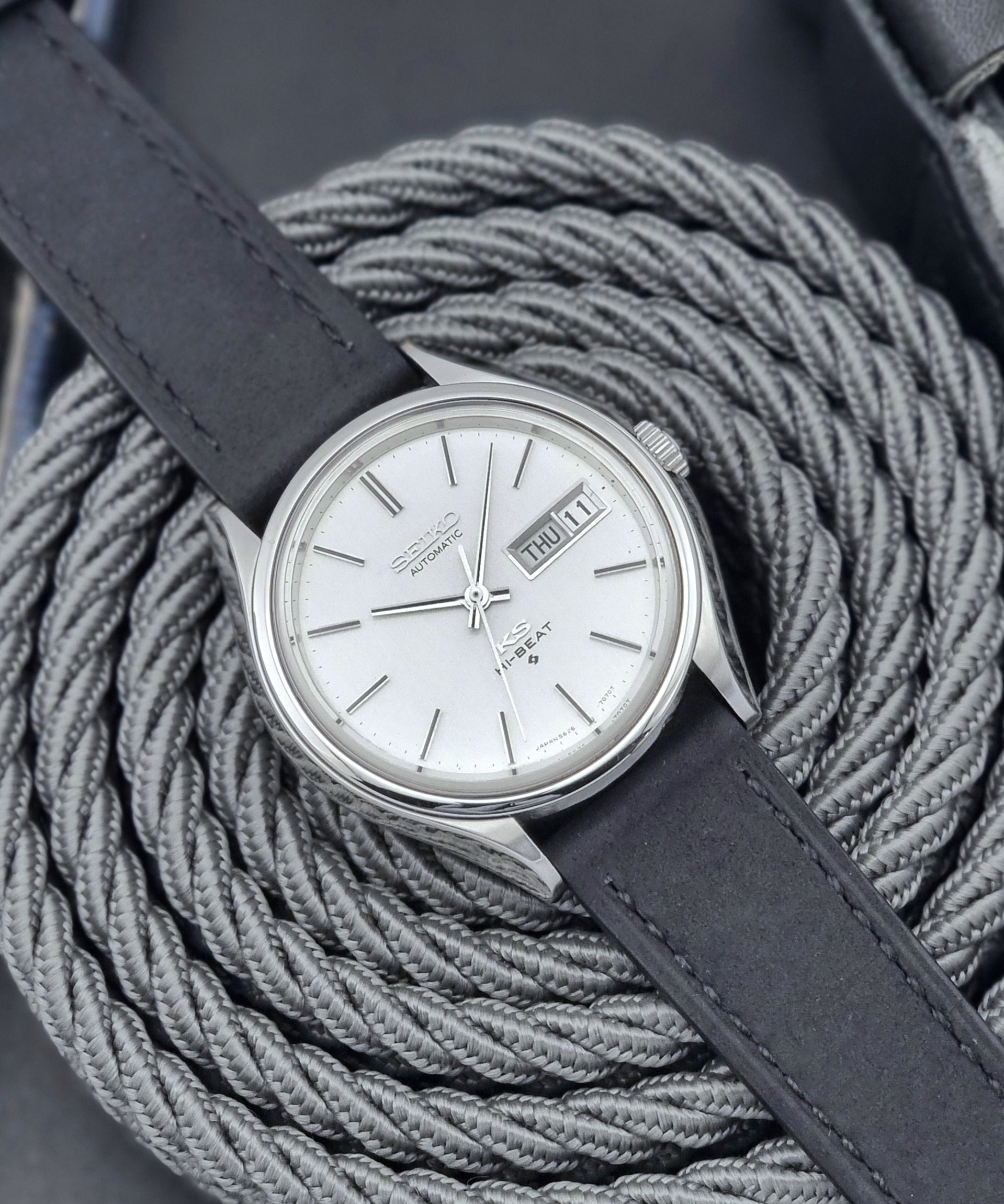 Vintage King Seiko Wristwatch Hi-beat 5626-7120 with a black strap on a textured gray background