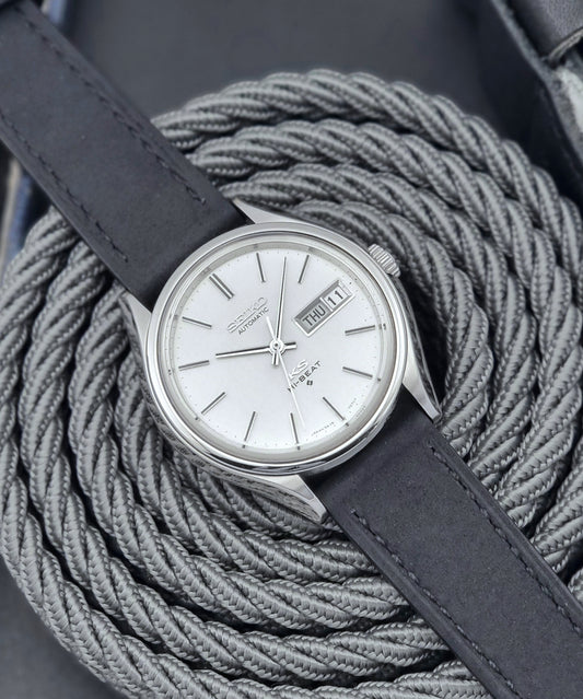 Vintage King Seiko Wristwatch Hi-beat 5626-7120 with a black strap on a textured gray background