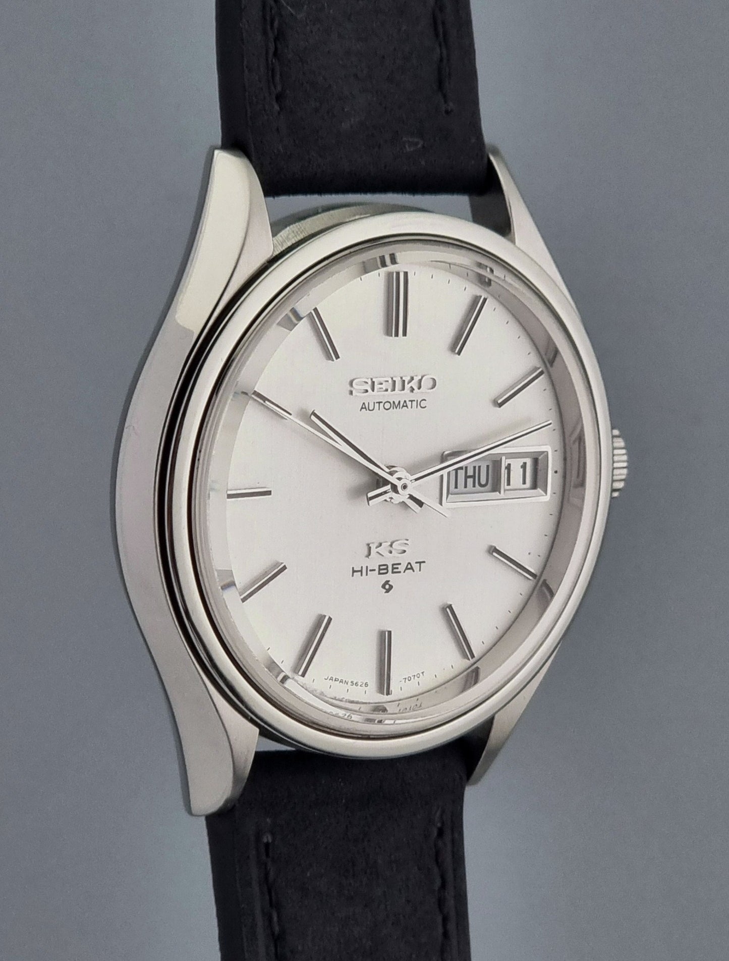 Vintage King Seiko Wristwatch Hi-beat 5626-7120 with a black strap on a grey background side profile