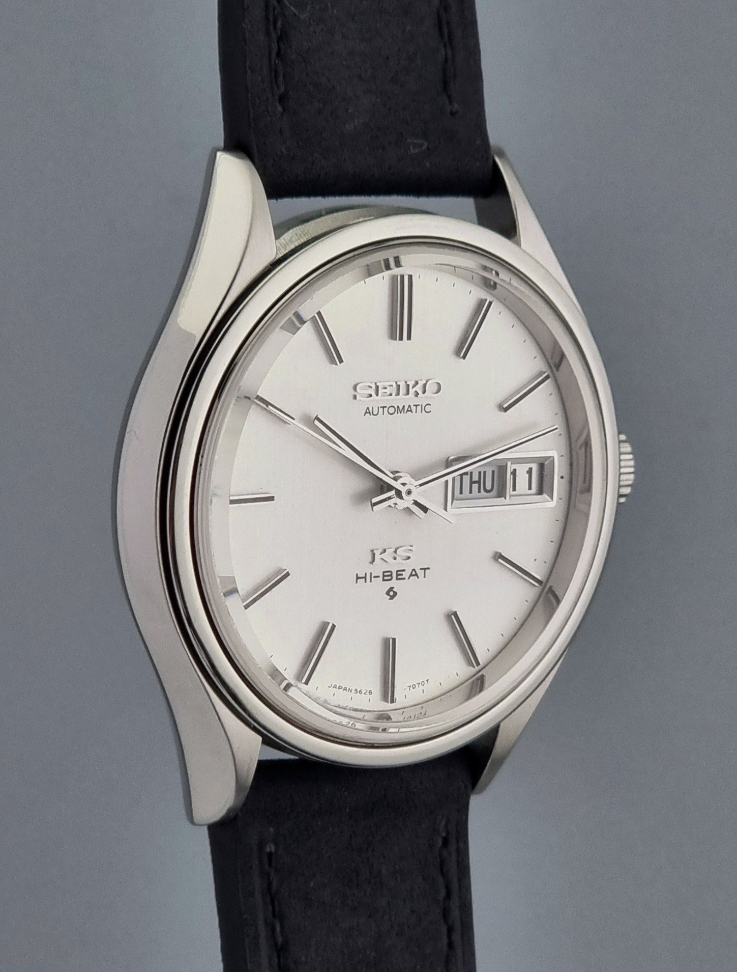 Vintage King Seiko Wristwatch Hi-beat 5626-7120 with a black strap on a grey background side profile