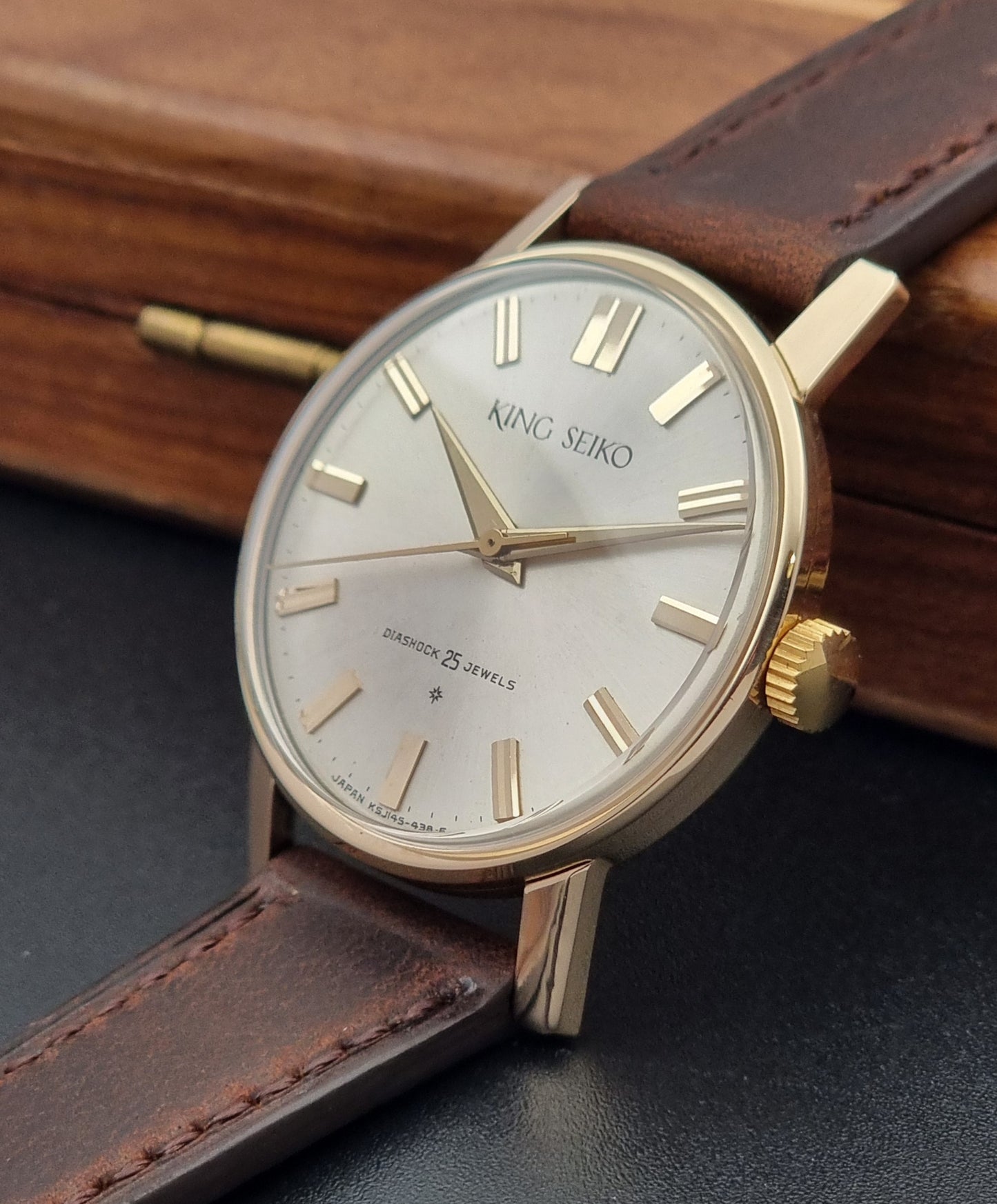 Vintage King Seiko Watch J14102 with brown leather strap on a wooden surface crown side view