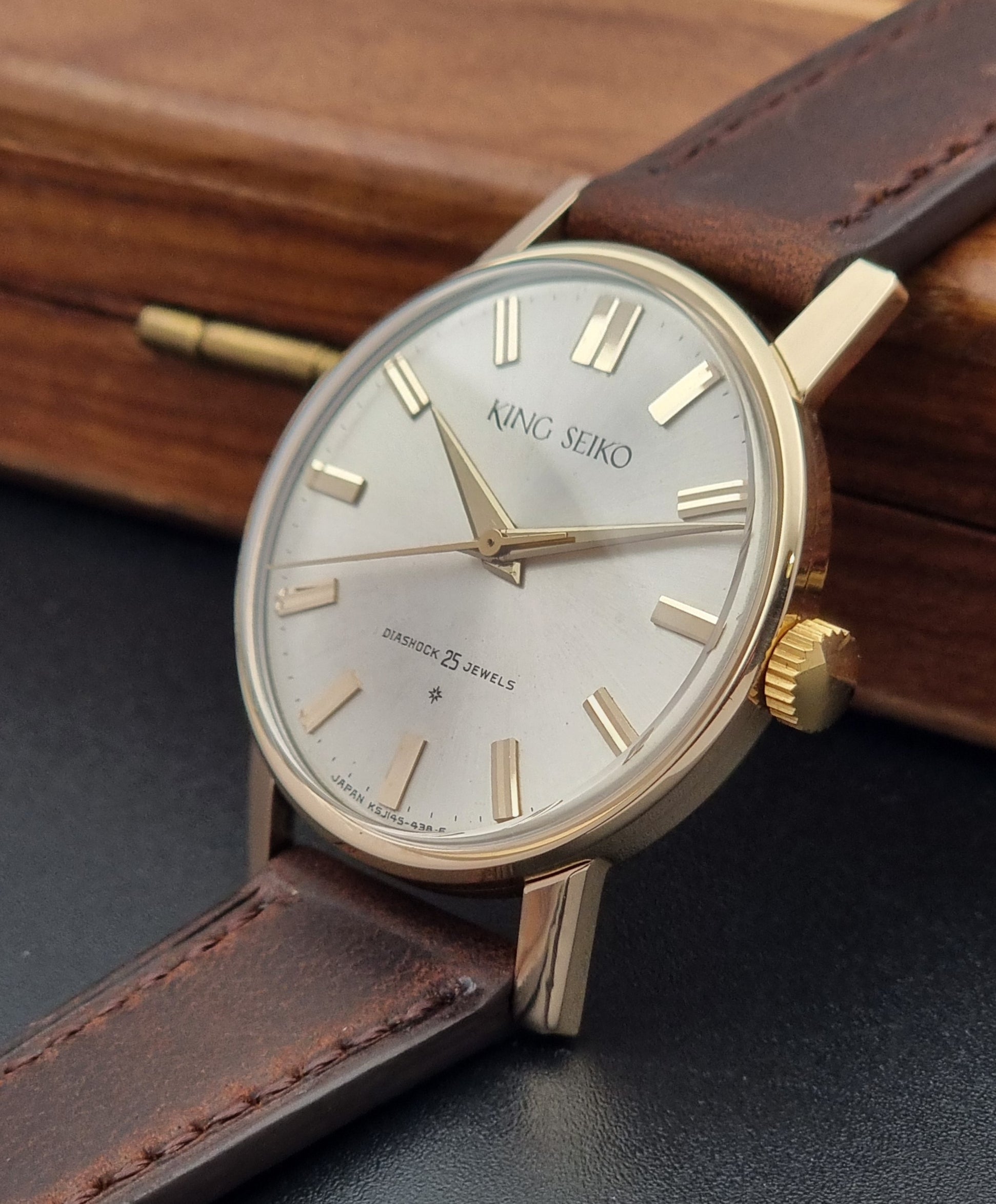 Vintage King Seiko Watch J14102 with brown leather strap on a wooden surface crown side view