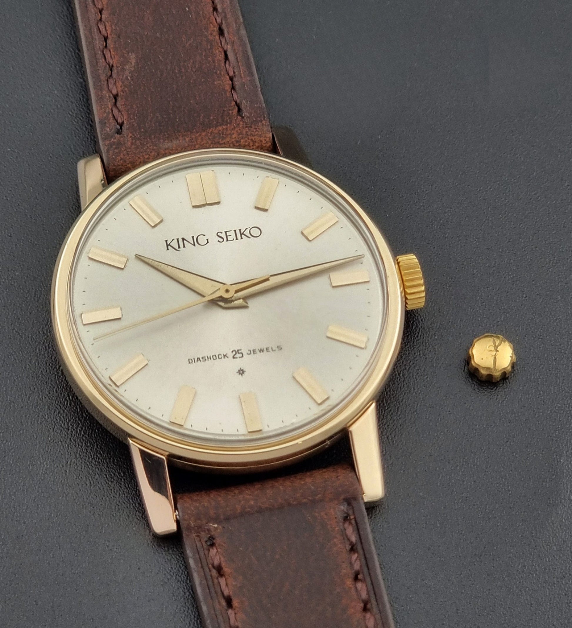 Vintage King Seiko Watch J14102 with brown leather strap on a wooden surface with the original crown