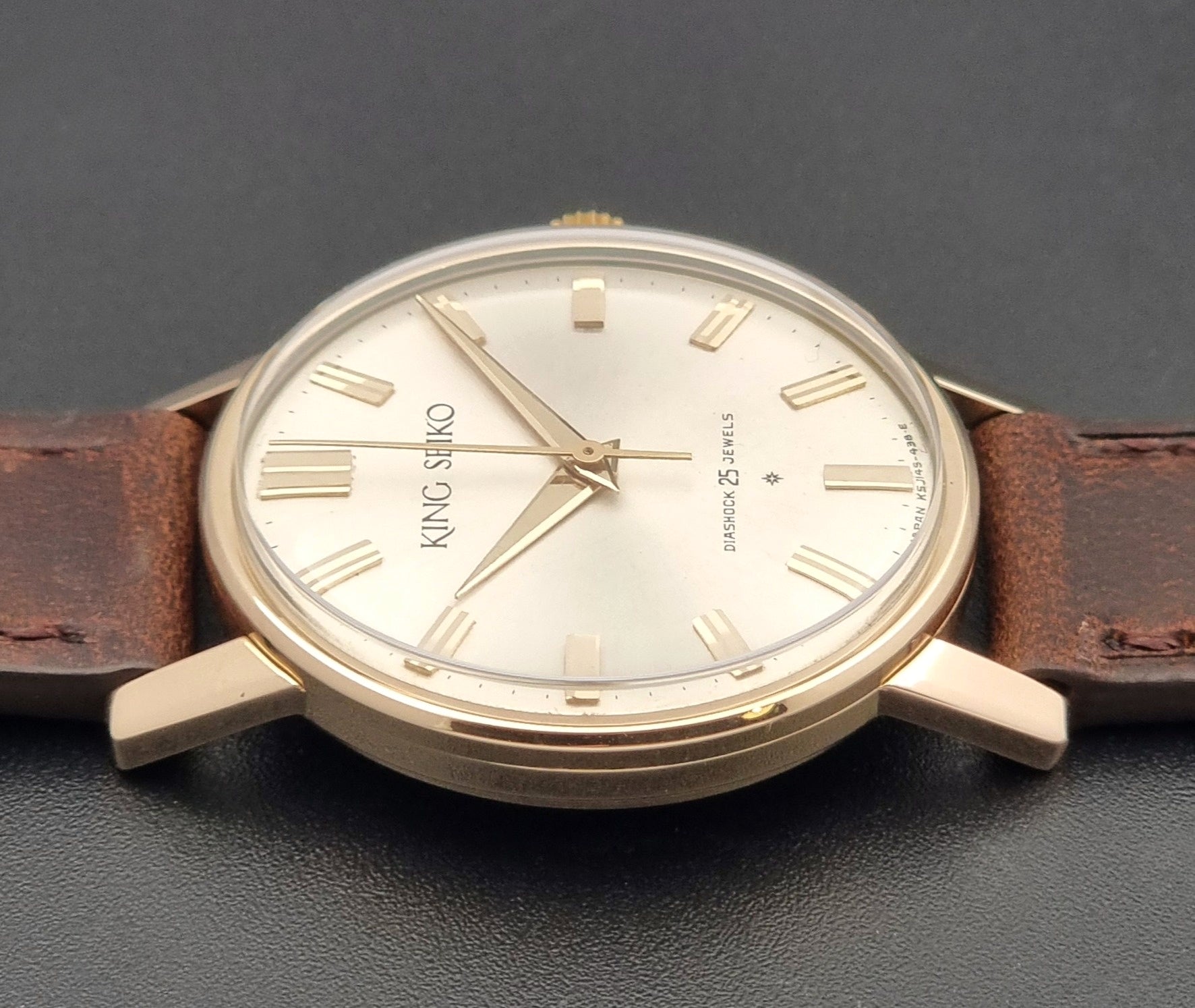 Vintage King Seiko Watch J14102 with brown leather strap on a wooden surface side view