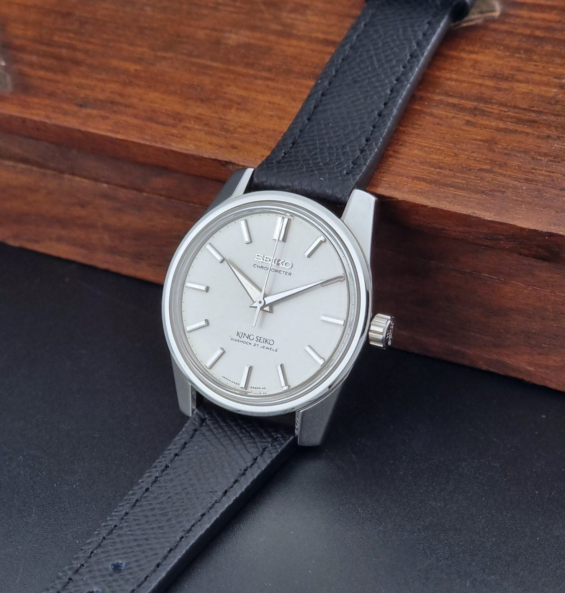 Vintage King Seiko Wristwatch 4420-9990 Chronometer with a black strap on a textured background crown view