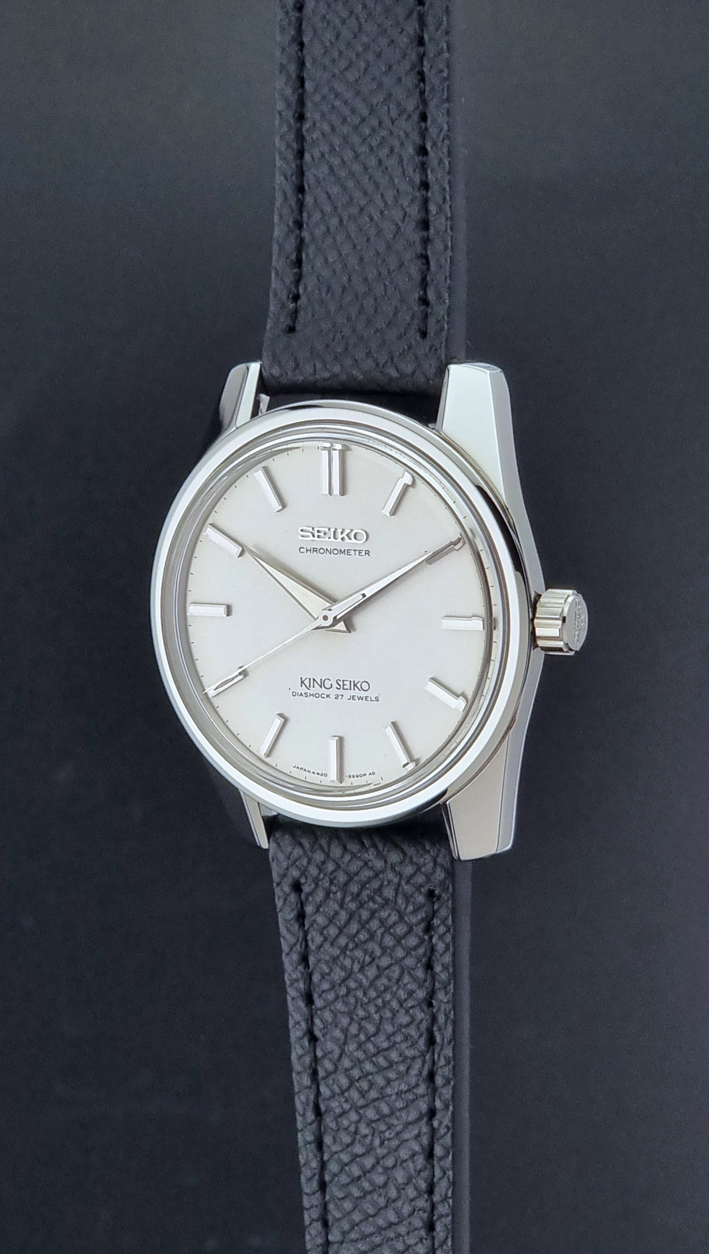 Vintage King Seiko Wristwatch 4420-9990 Chronometer with a black strap on a textured background crown profile view