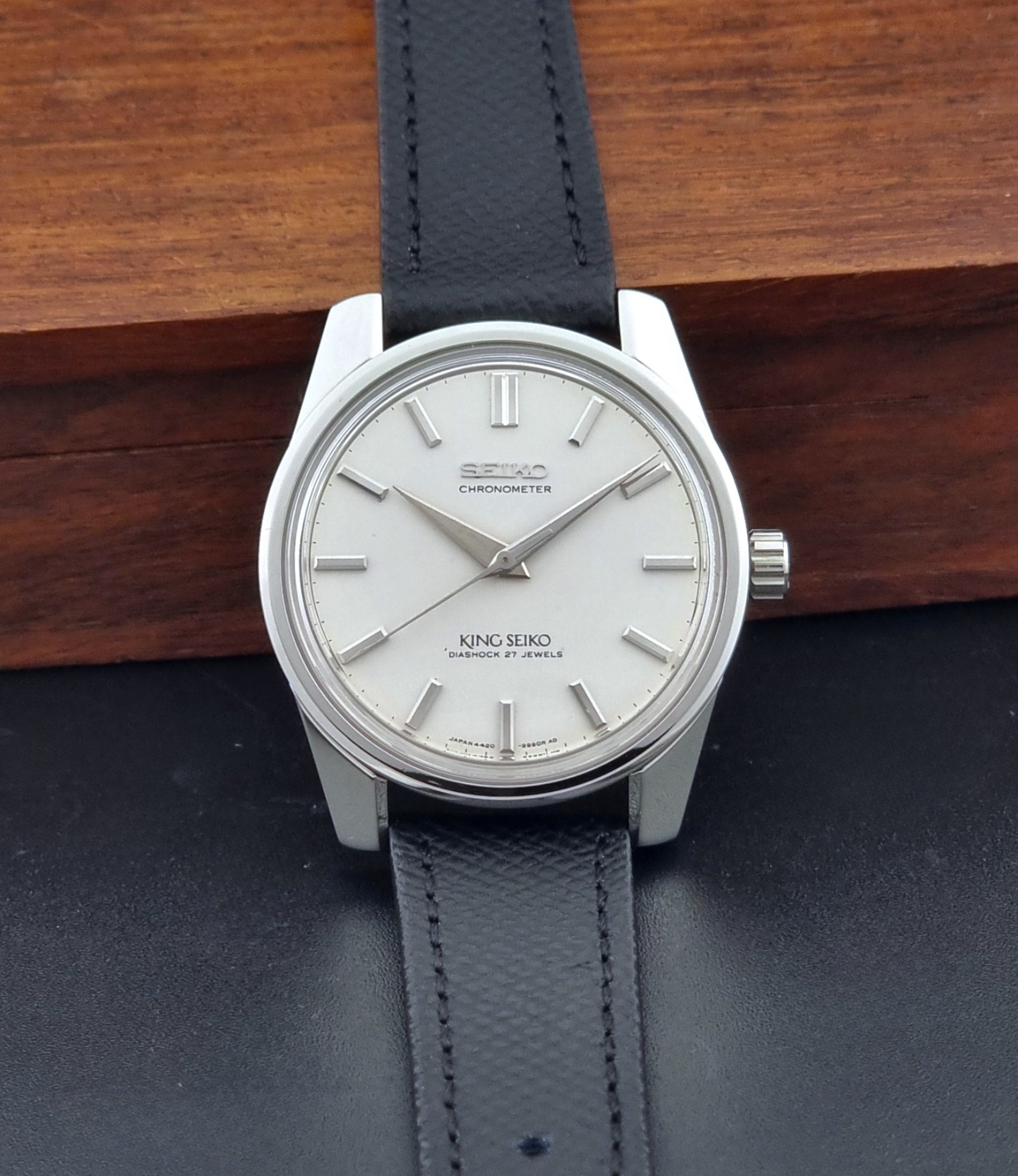 Vintage King Seiko Wristwatch 4420-9990 Chronometer with a black strap on a textured background dial view