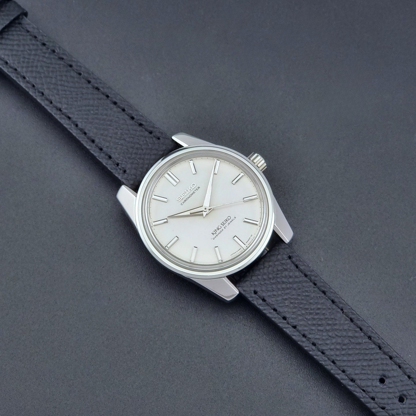 Vintage King Seiko Wristwatch 4420-9990 Chronometer with a black strap on a textured background dial