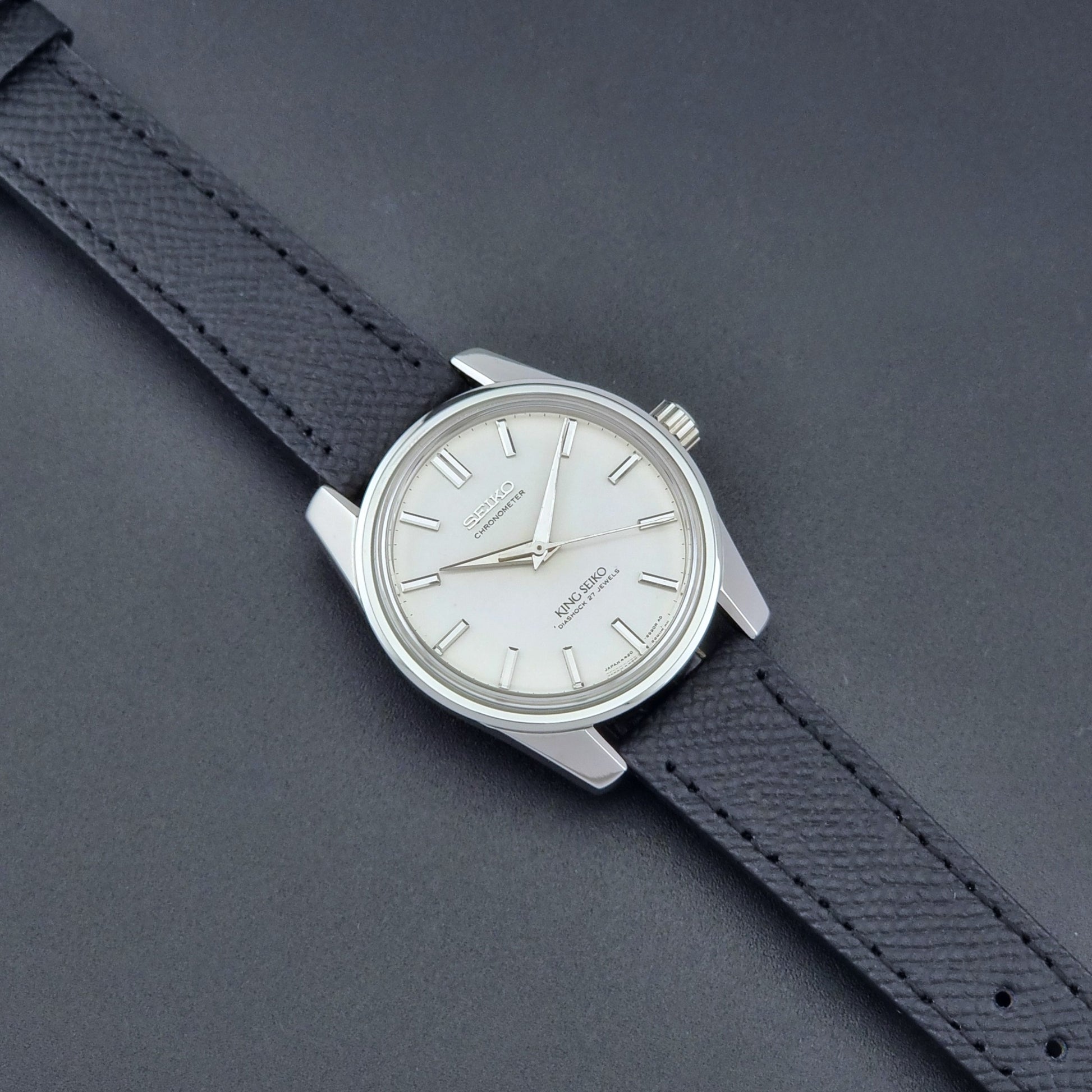 Vintage King Seiko Wristwatch 4420-9990 Chronometer with a black strap on a textured background dial