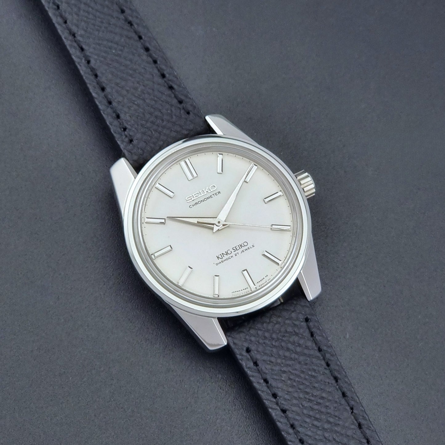 Vintage King Seiko Wristwatch 4420-9990 Chronometer with a black strap on a textured background close up dial view