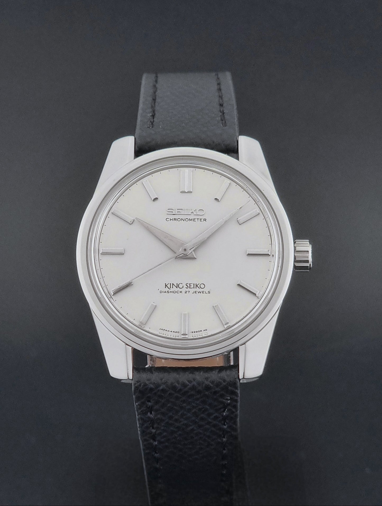 Vintage King Seiko Wristwatch 4420-9990 Chronometer with a black strap on a textured background close dial view