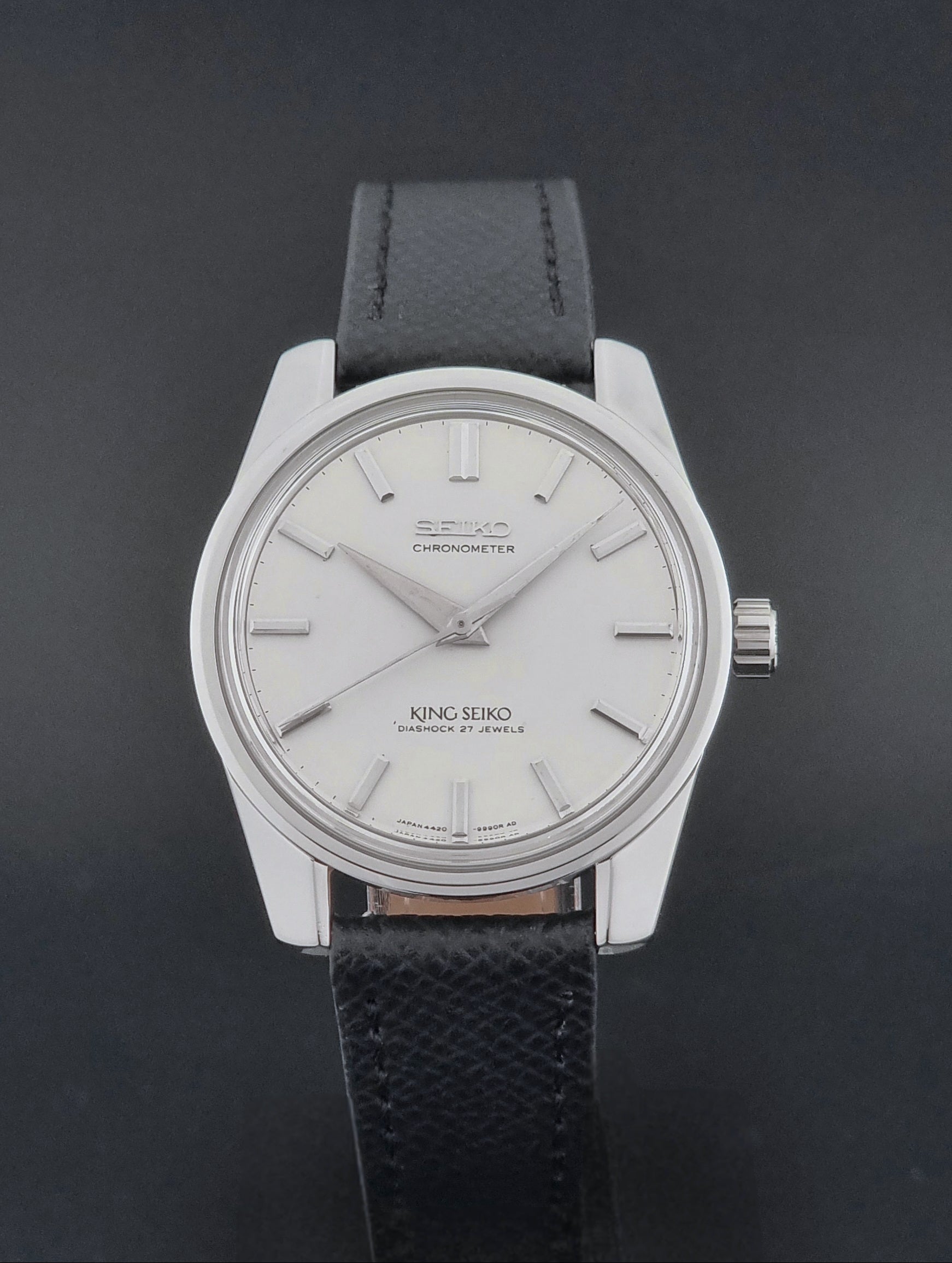 Vintage King Seiko Wristwatch 4420-9990 Chronometer with a black strap on a textured background close dial view