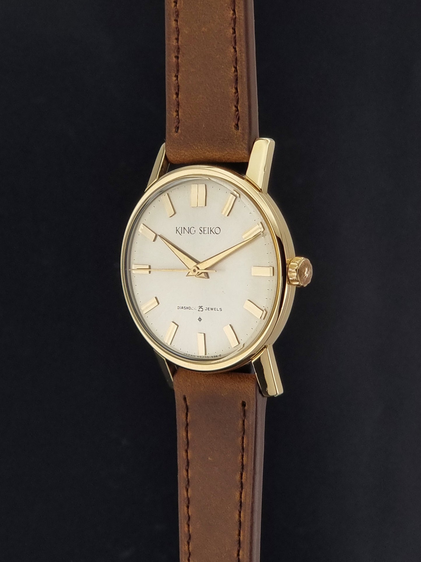 Vintage King Seiko J14102E Watch with brown leather strap on a dark gray background crown profile view