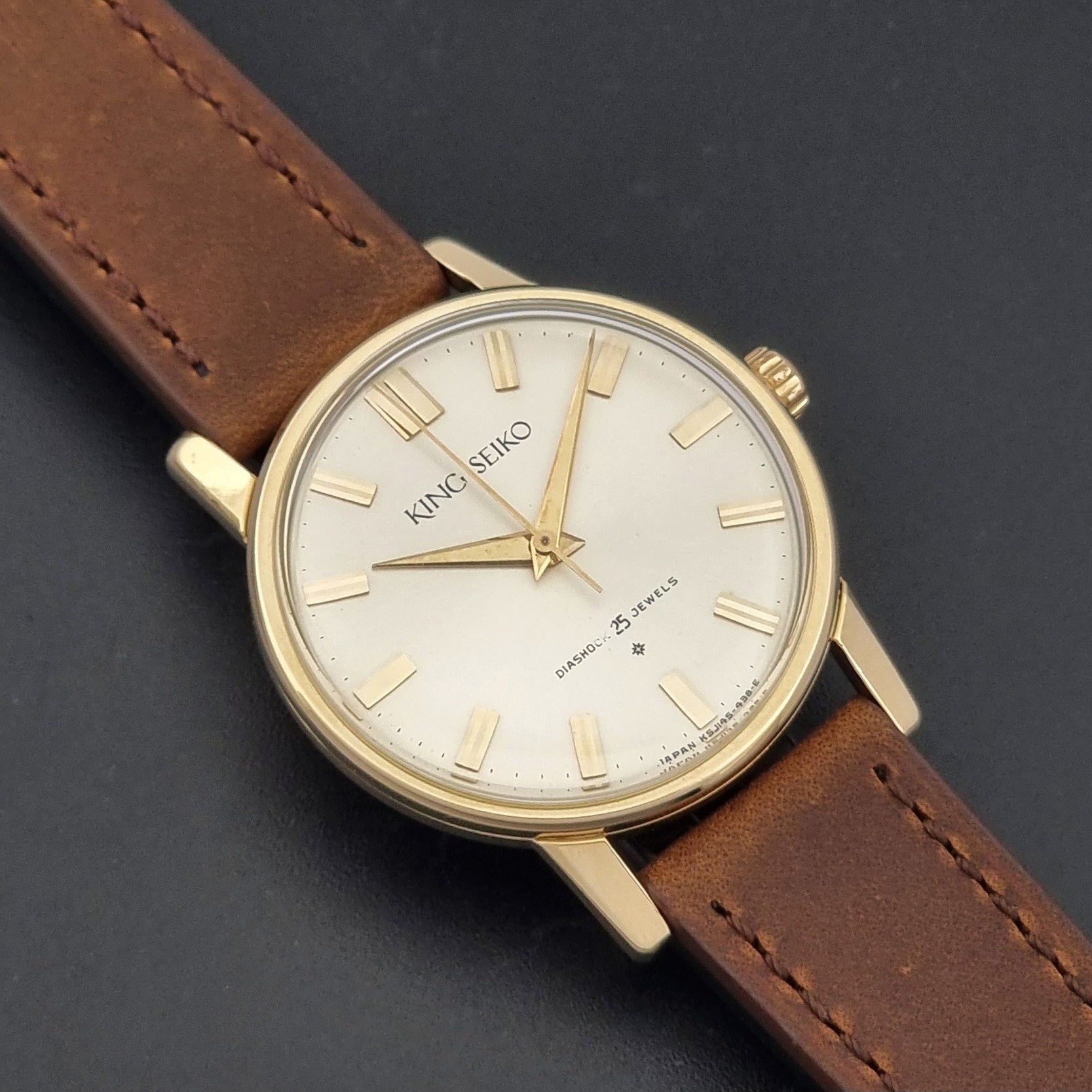 Vintage King Seiko J14102E Watch with brown leather strap on a dark gray background close up dial view