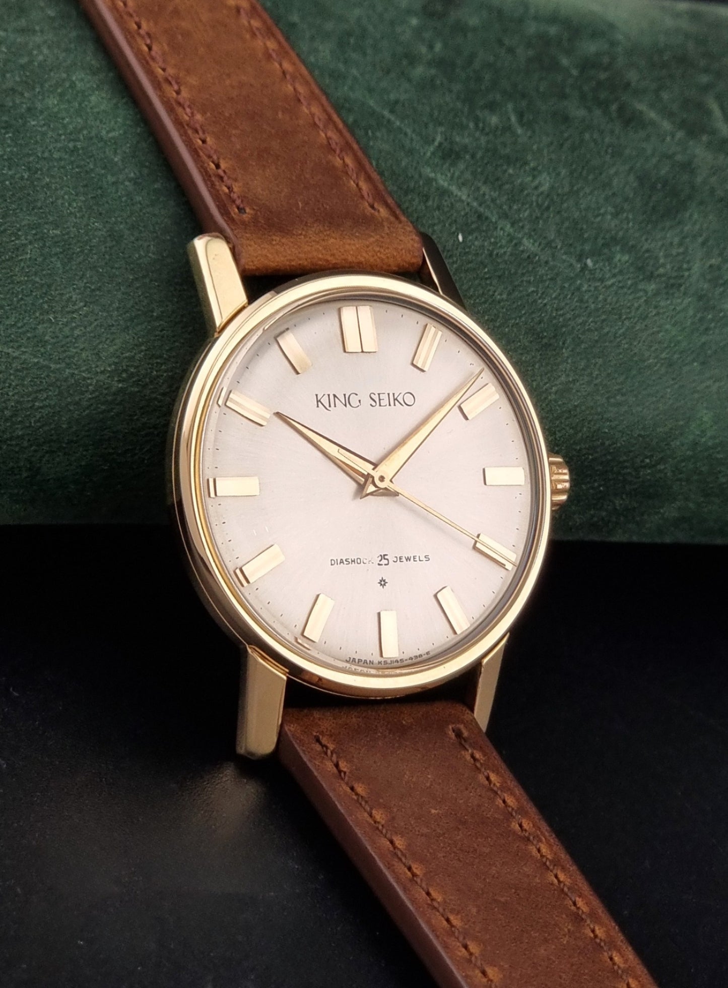 Vintage King Seiko J14102E Watch with brown leather strap on a dark gray background side view