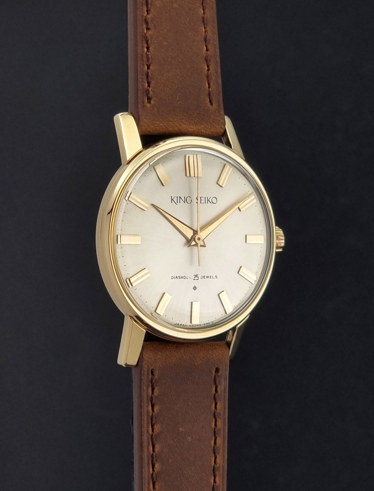 Vintage King Seiko J14102E Watch with brown leather strap on a dark gray background side profile view
