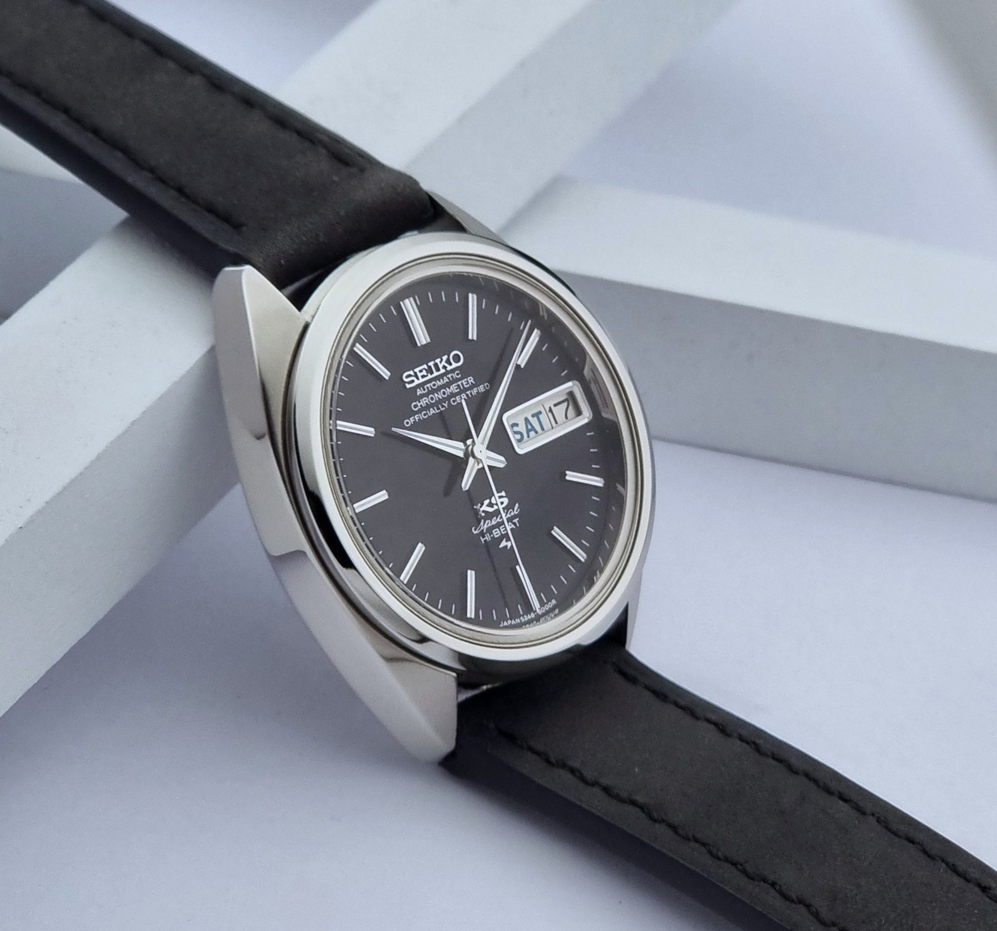 Vintage King Seiko Watch Special 5246-6000 with black leather strap on a light gray background side view
