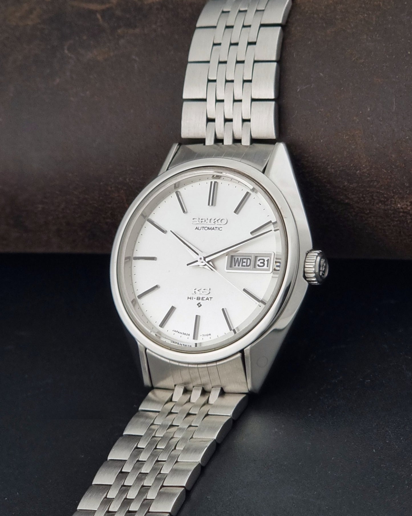 A vintage Seiko automatic watch with a silver stainless steel case and link bracelet, featuring a white dial with silver baton indices and a day-date window.